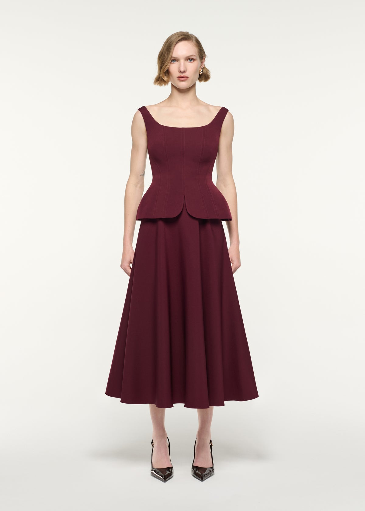 Front view of a model wearing the Crepe Peplum Midi Dress
