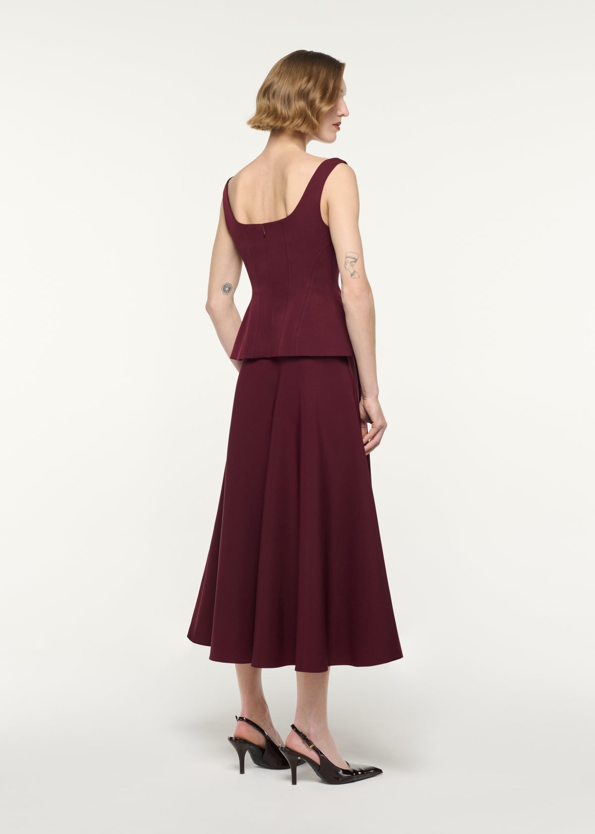Back view of a model wearing the Crepe Peplum Midi Dress