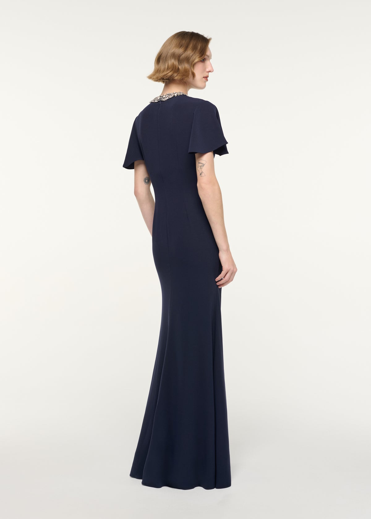 Back view of a model wearing the Crystal Neckline Draped Sleeve Gown