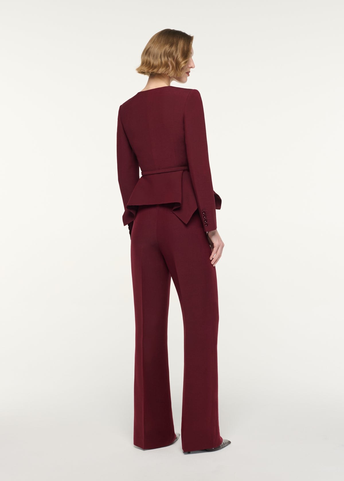 Back view of a model wearing the Origami Drape Peplum Jacket