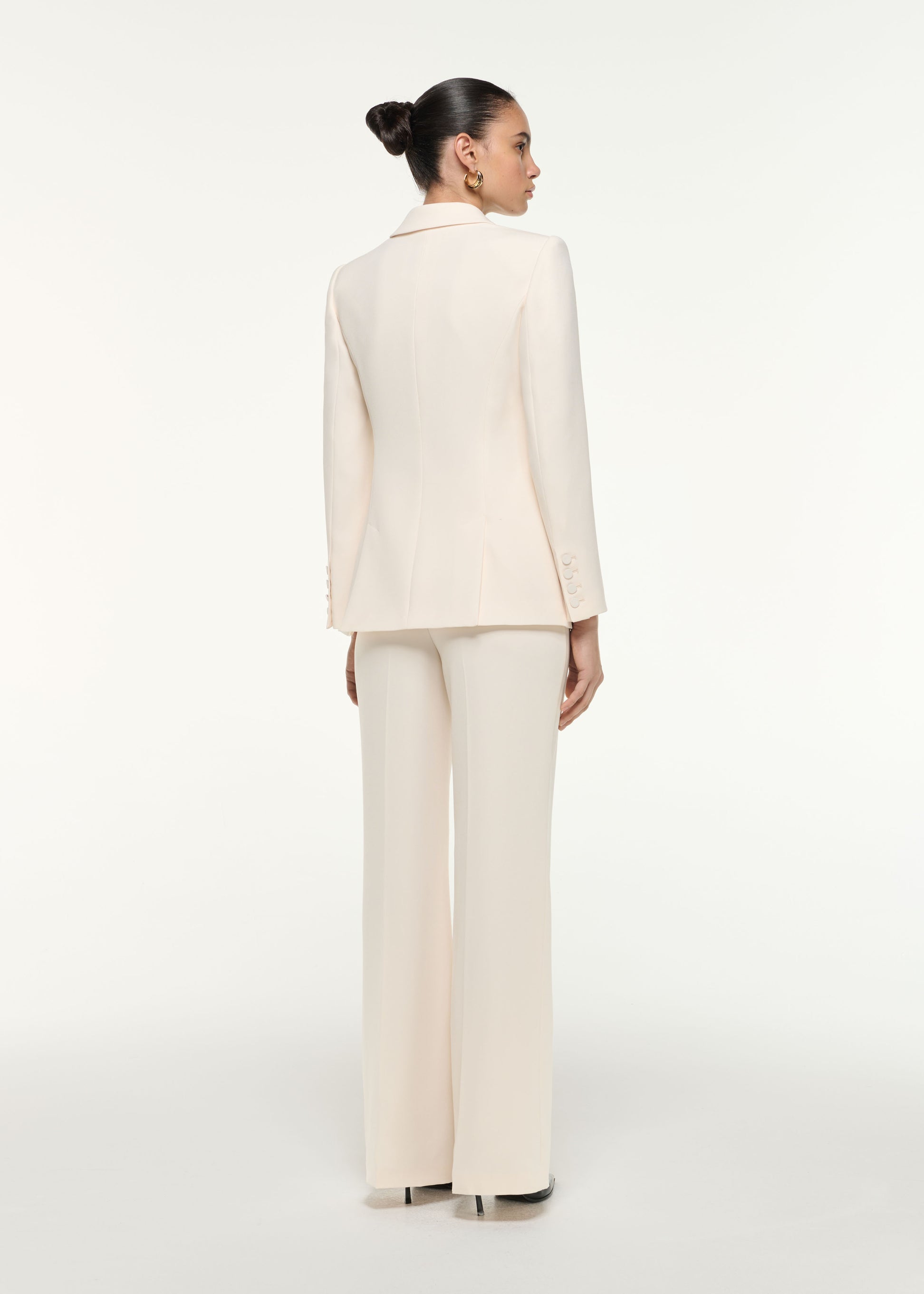 Back view of a model wearing the Satin Crepe Tailored Jacket in Cream