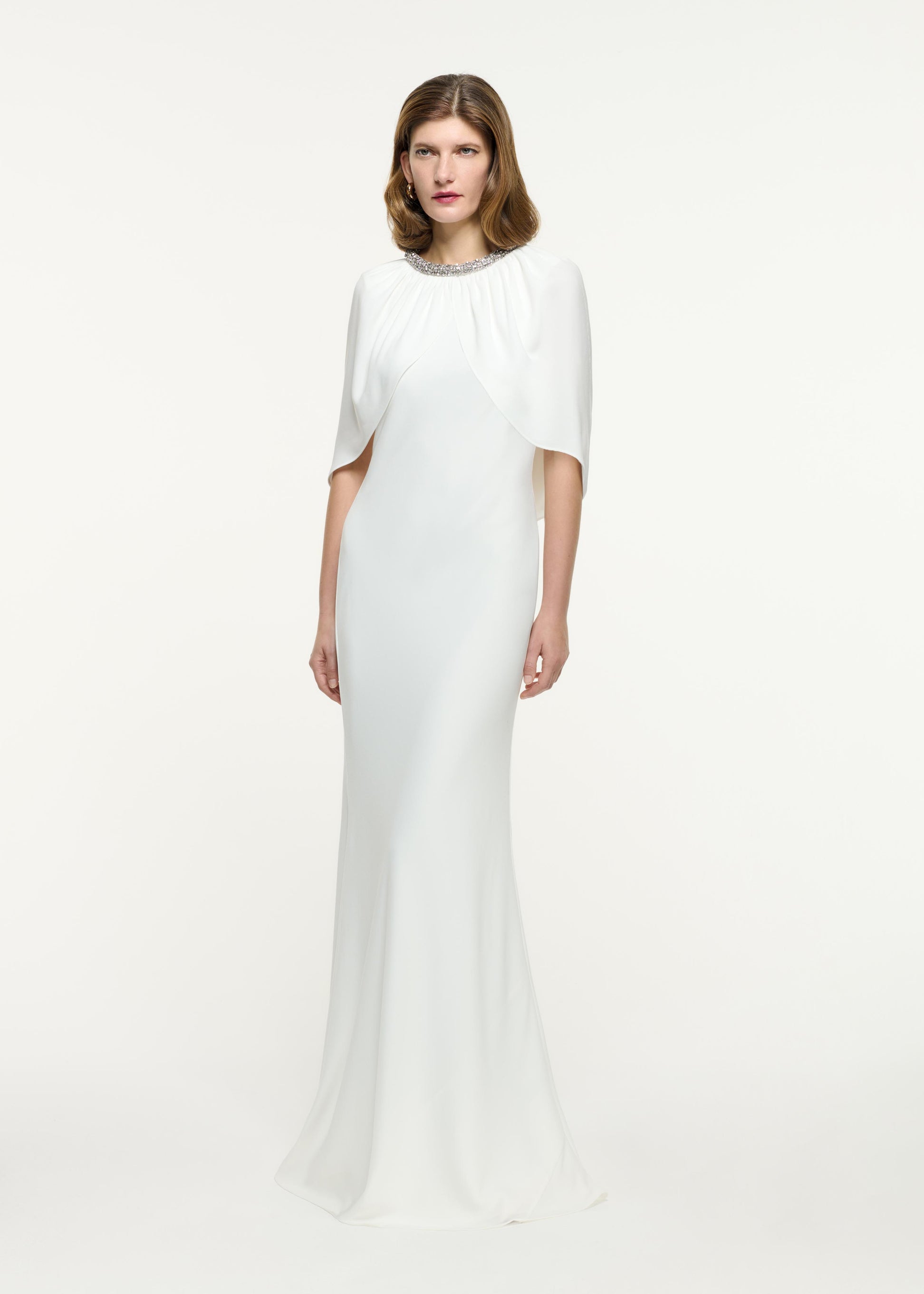 Side view of a model wearing the Embellished Cape Satin Crepe Gown in White
