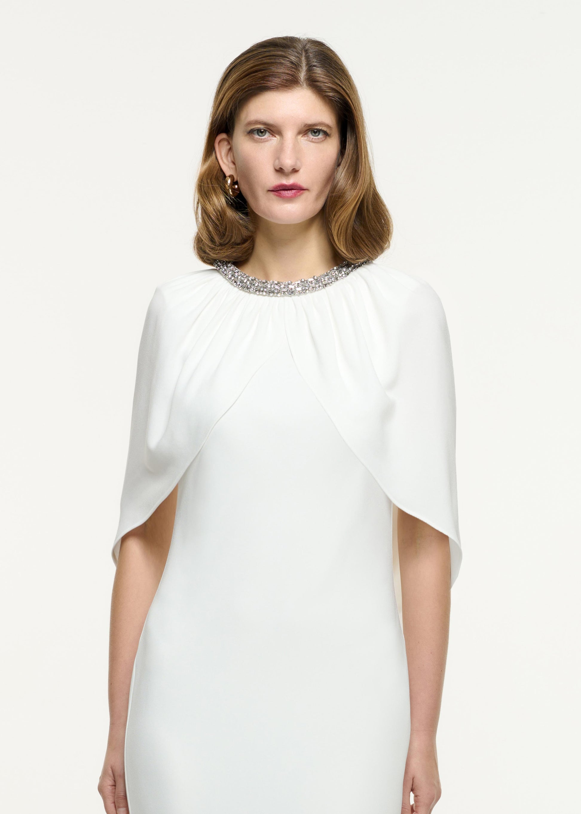 Close up of a model wearing the Embellished Cape Satin Crepe Gown in White