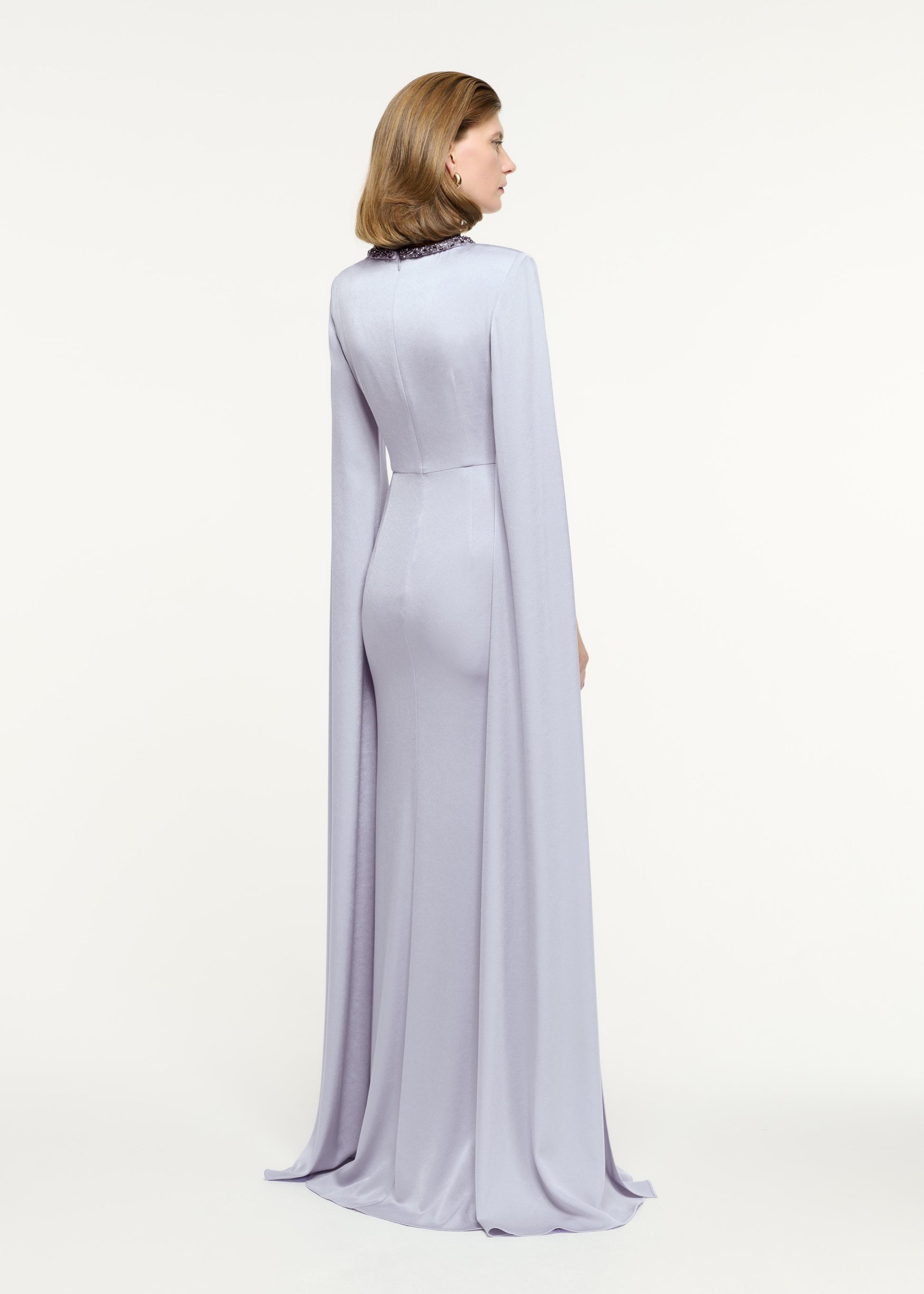 Back view of a model wearing the Cape Sleeve Embellished Gown in Lavender