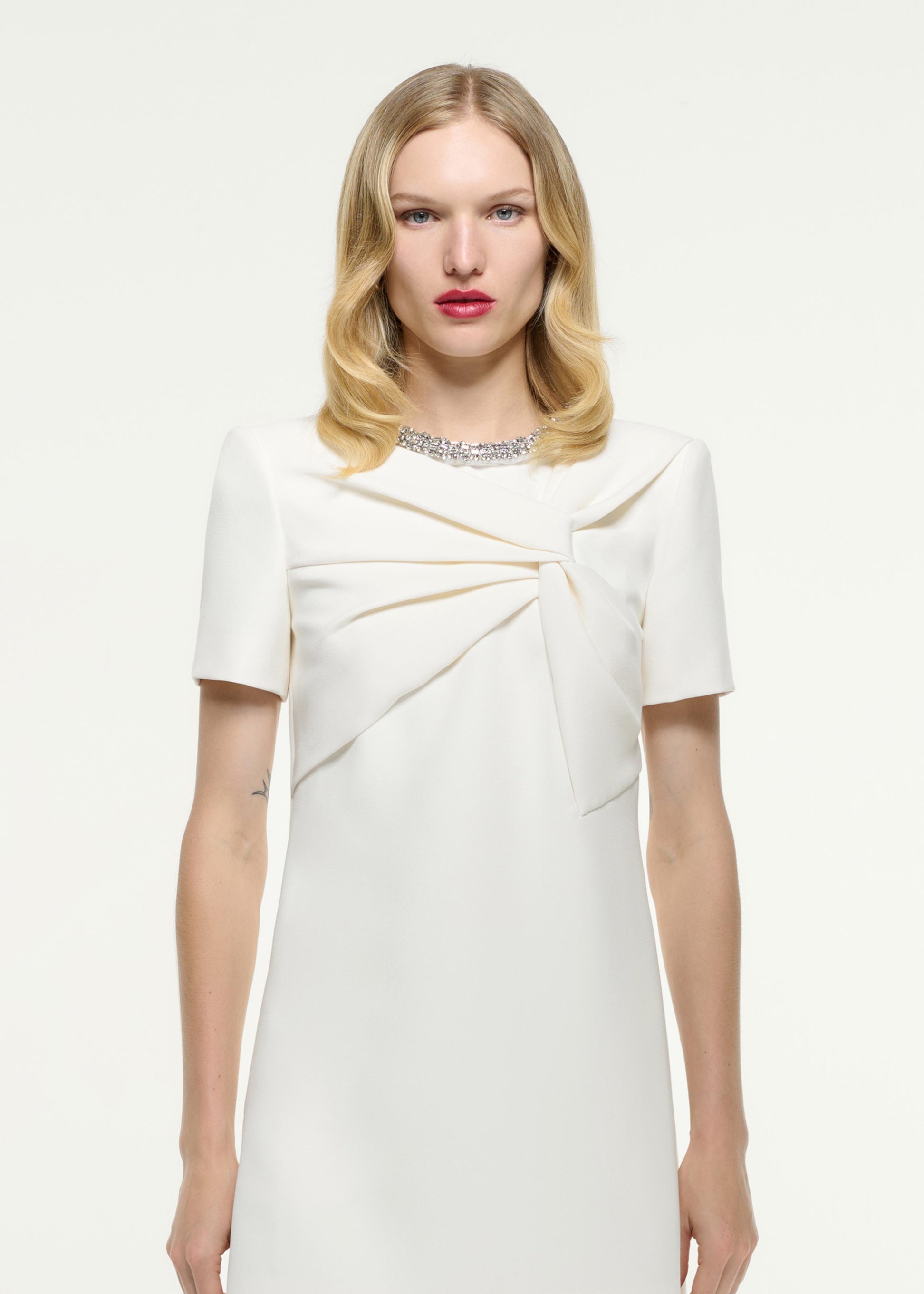 Close up of a model wearing the Short Sleeve Embellished Crepe Mini Dress in Cream