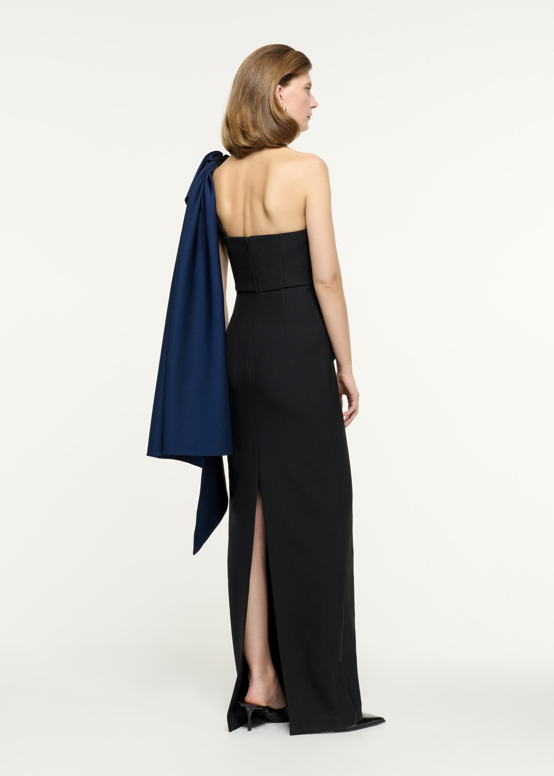 Back view of a model wearing the Asymmetric Taffeta Bow Drape Gown in Blue