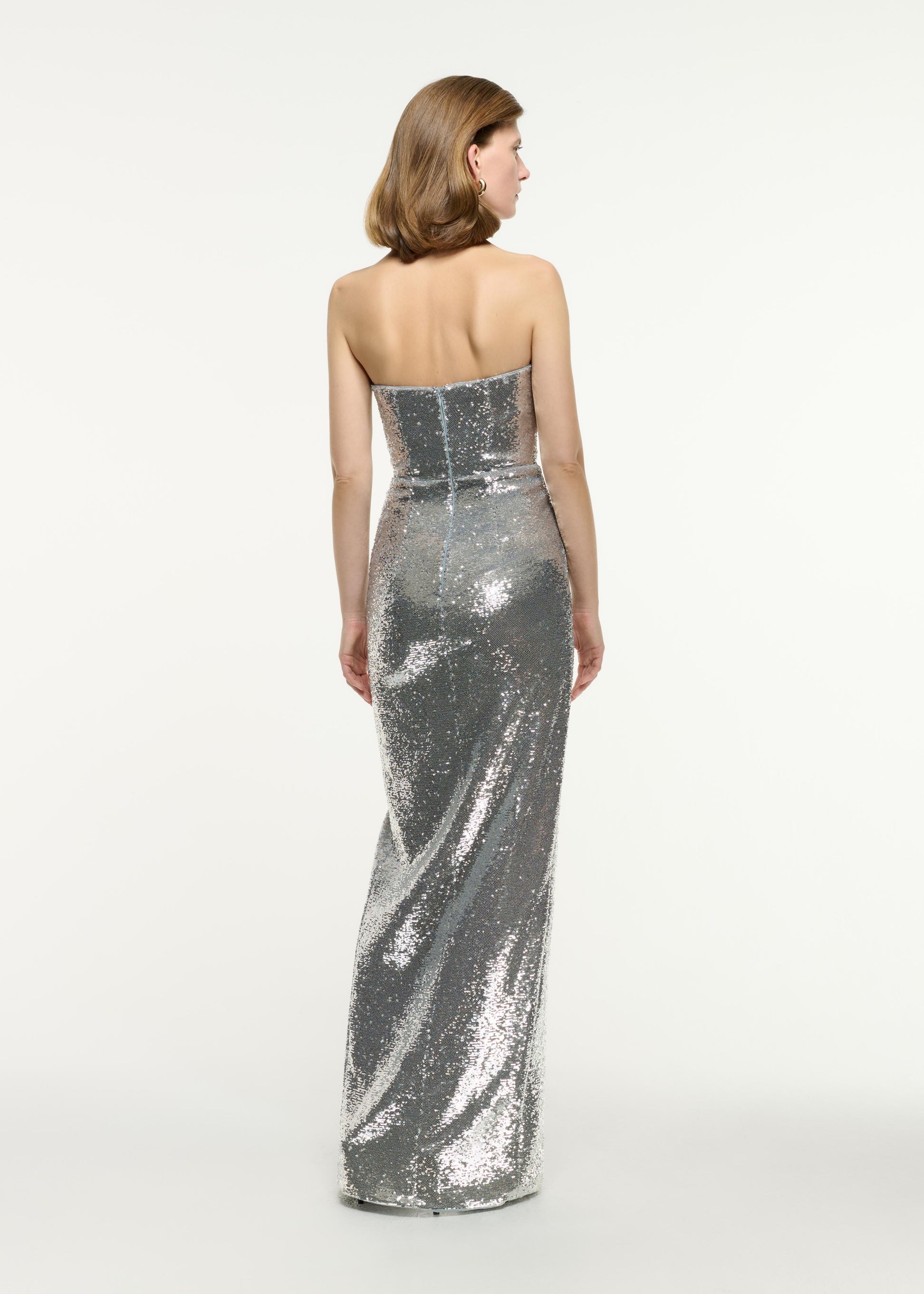 Back view of a model wearing the Strapless Sequin Buckle Gown in Silver