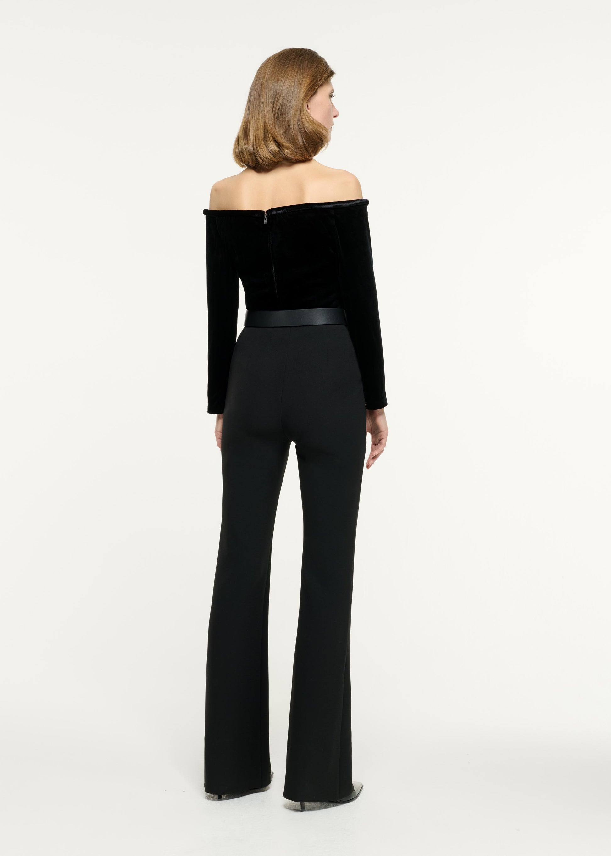 Back view of a model wearing the Off The Shoulder Velvet Top in Black