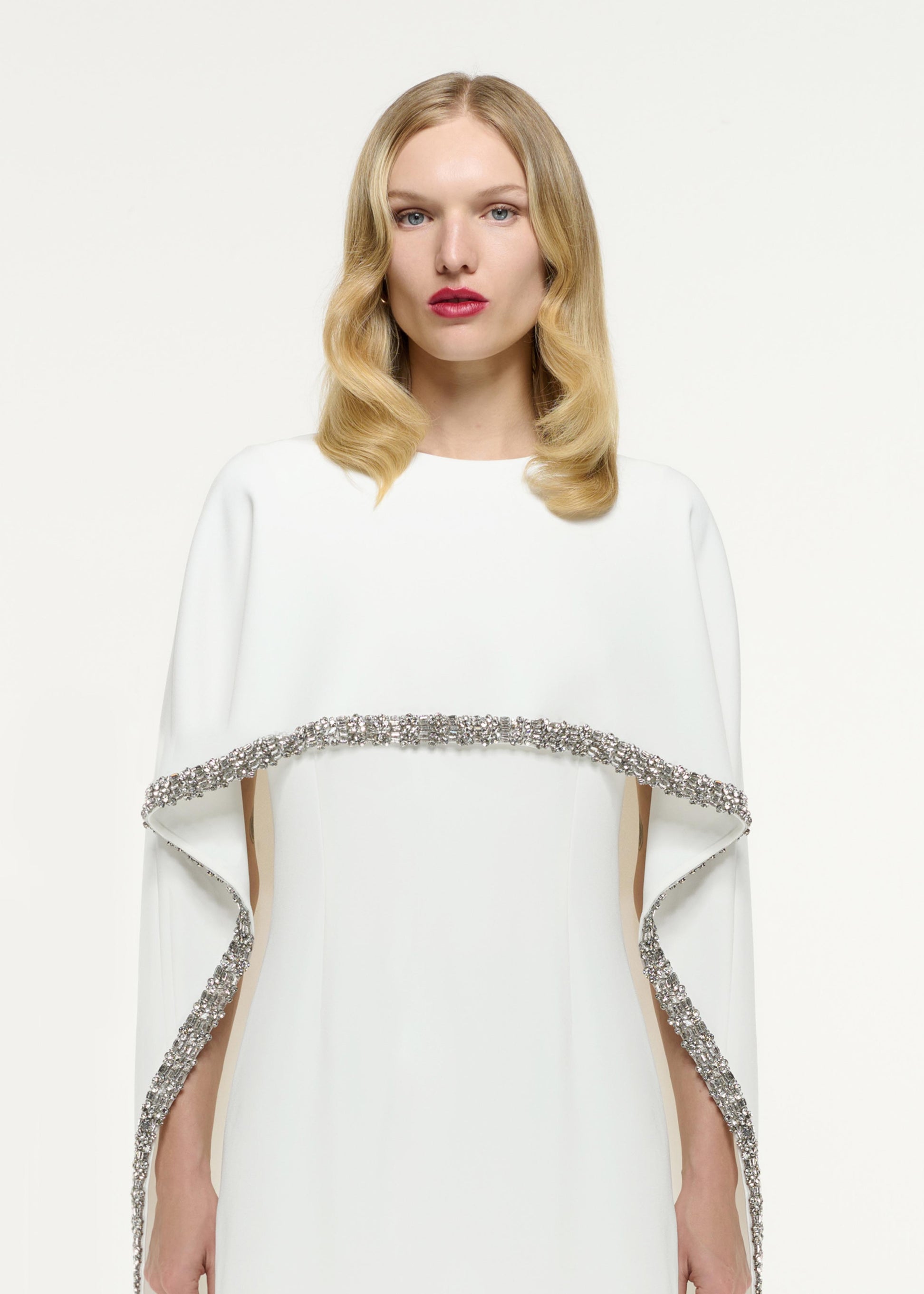 Close up of a model wearing the Embellished Cape Satin Crepe Mini Dress in White