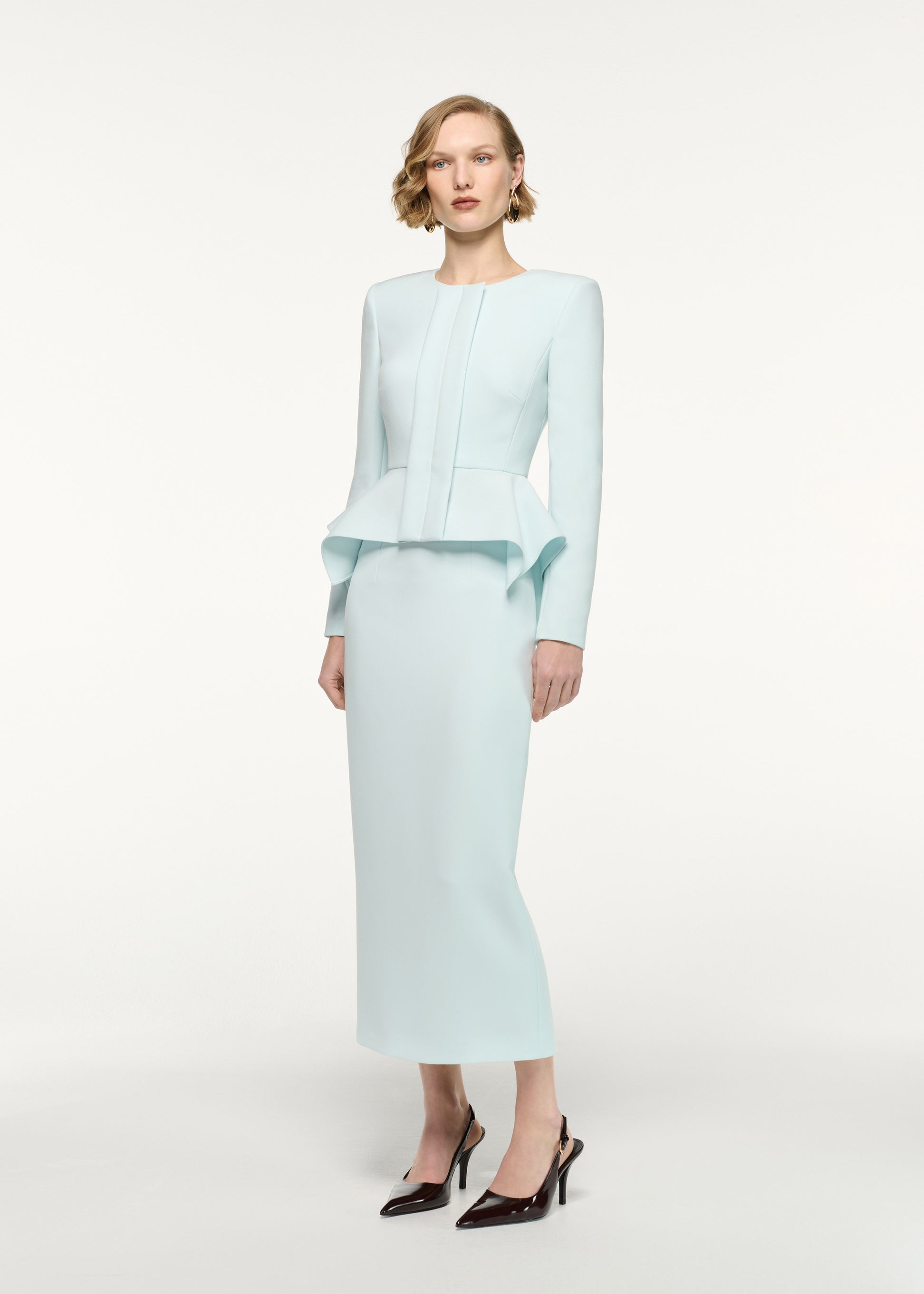 Side view of a model wearing the Peplum Crepe Jacket in Aqua