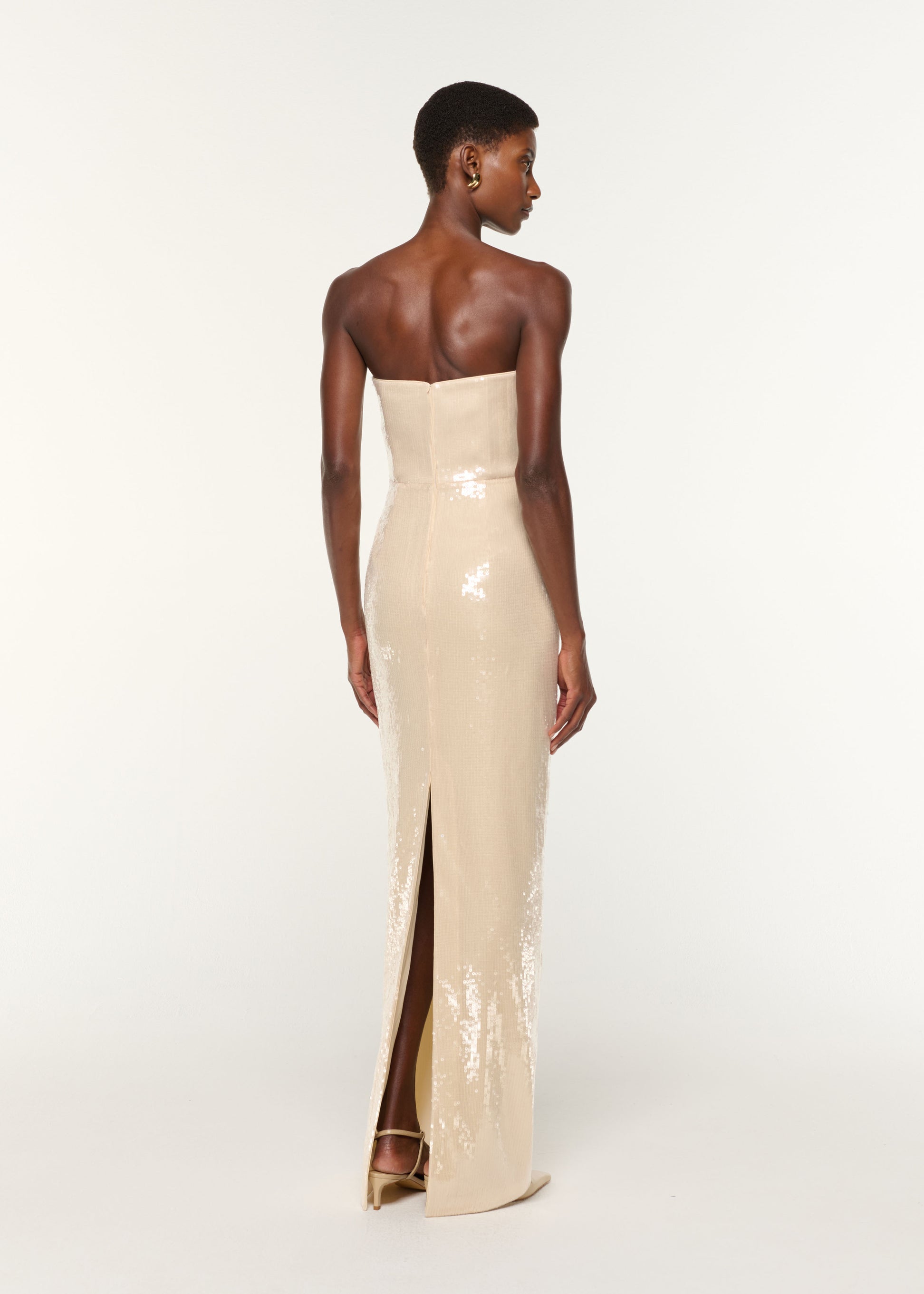 Back view of a model wearing the Curved Neckline Sequin Column Gown in Cream
