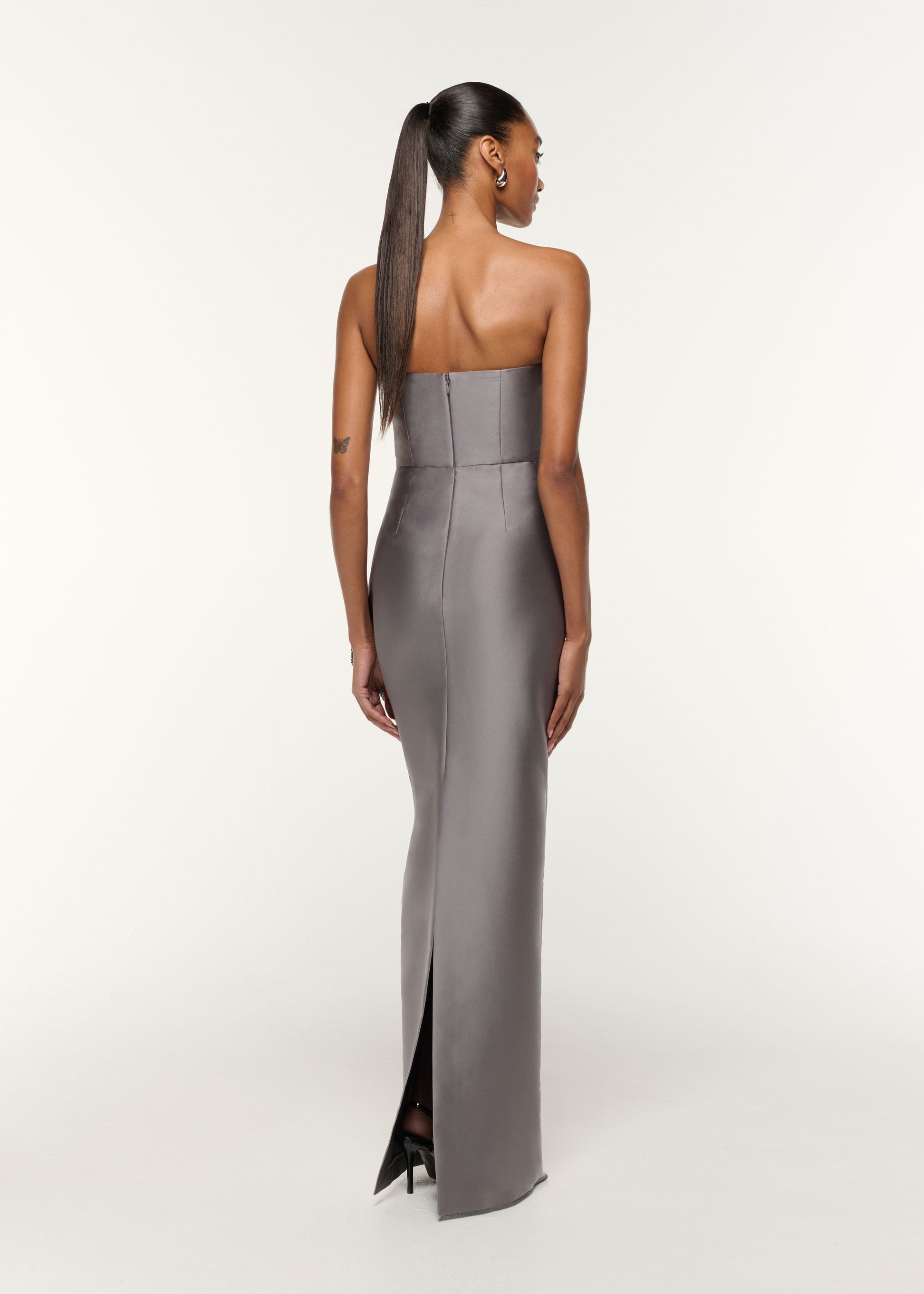 Back view of a model wearing the Square Neck With Crystal Trim Peplum Taffeta Gown in Grey