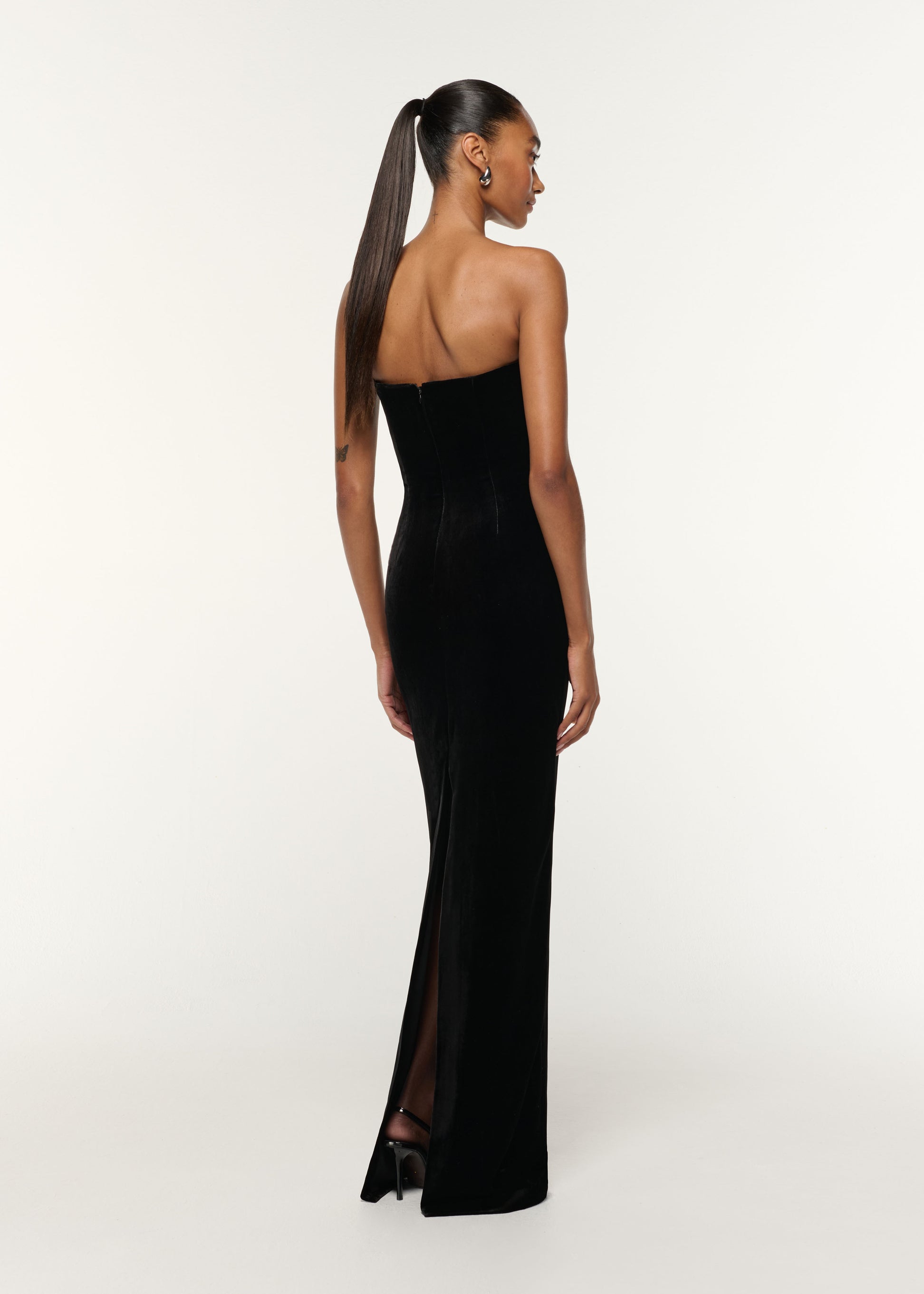 Back view of a model wearing the Diamante Twist Drape Velvet Column Gown in Black