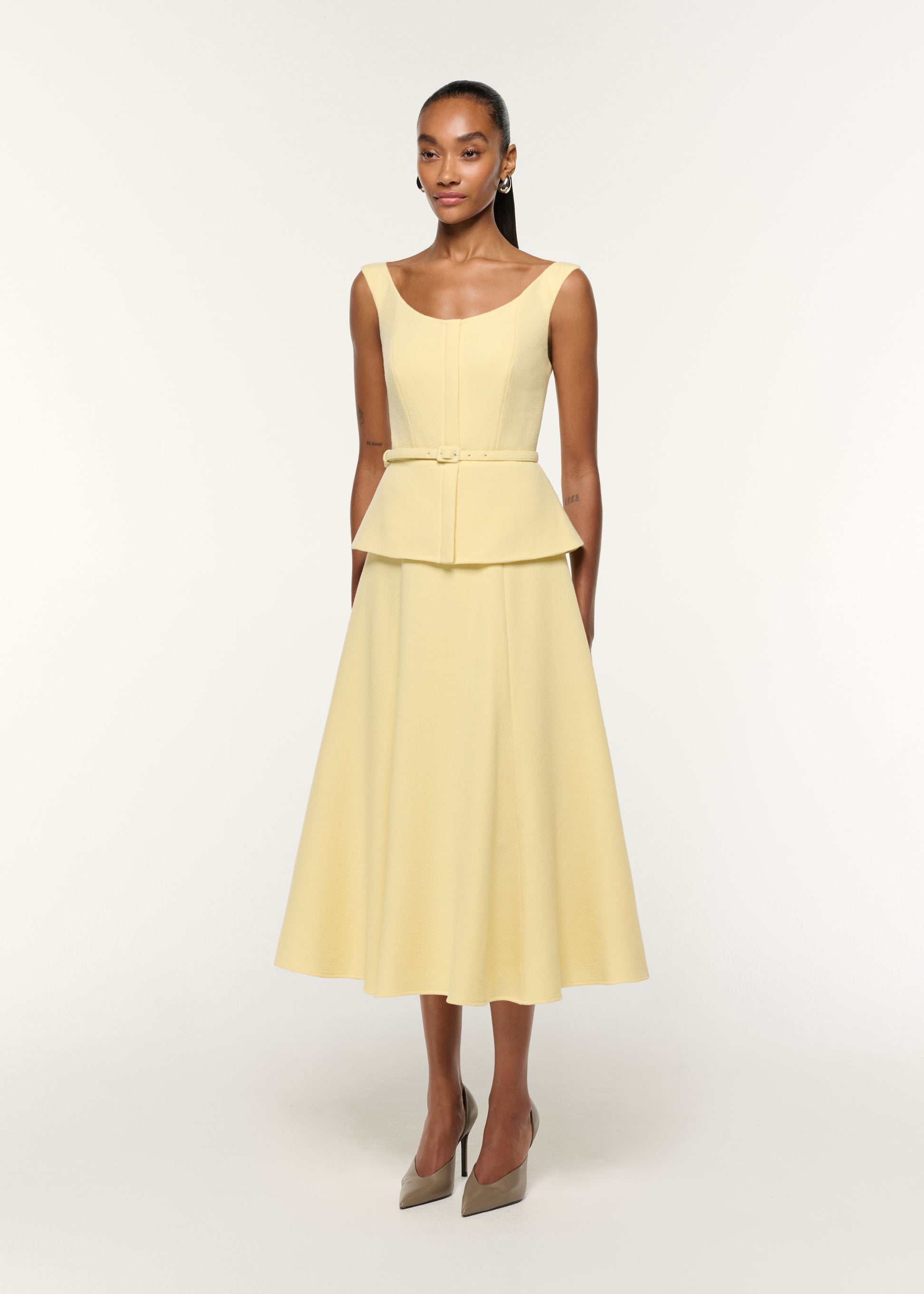 Side view of a model wearing the Structured Peplum Wool Crepe Dress in Yellow