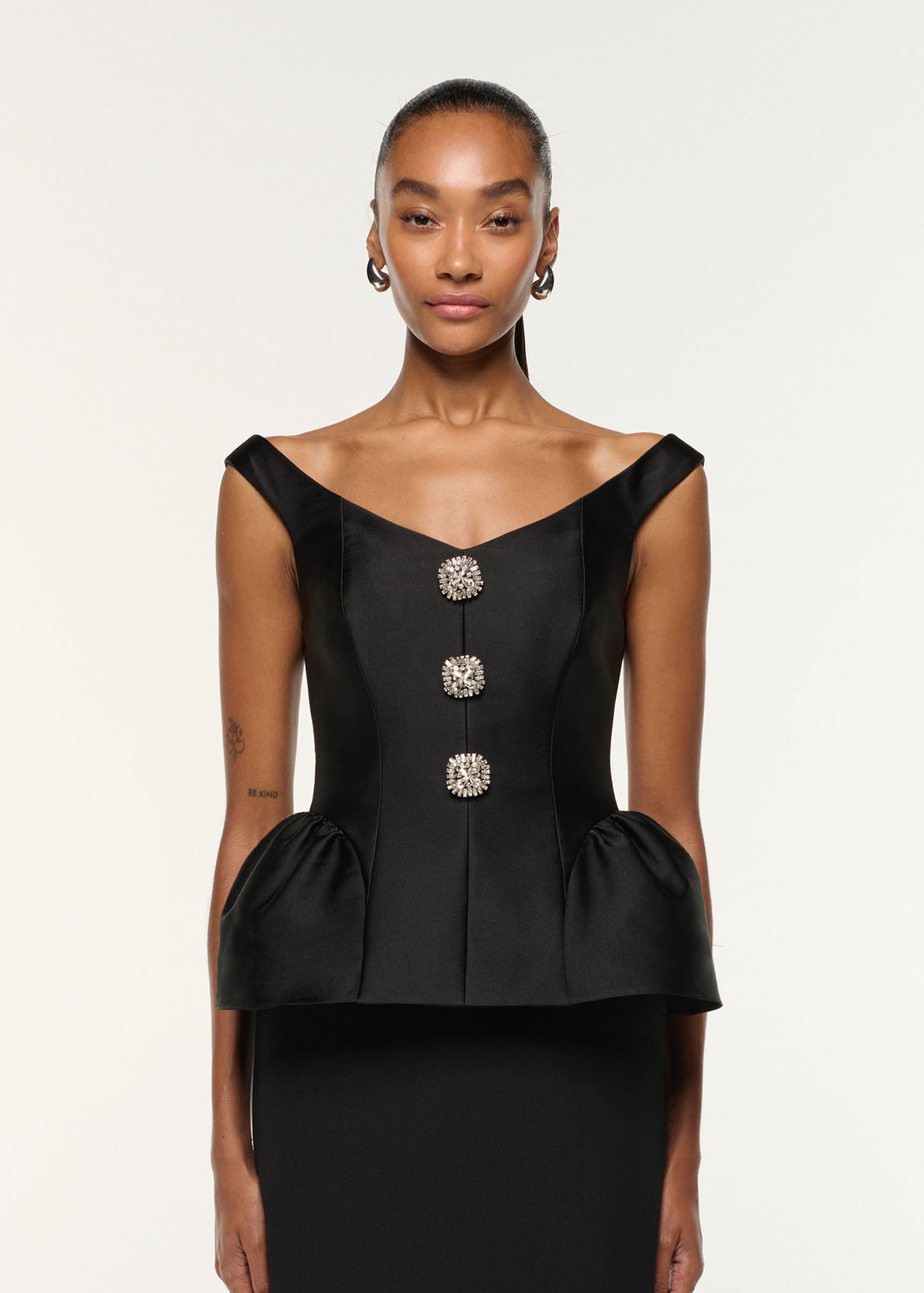 Close up of a model wearing the Crystal Button Peplum Taffeta Crepe Gown in Black