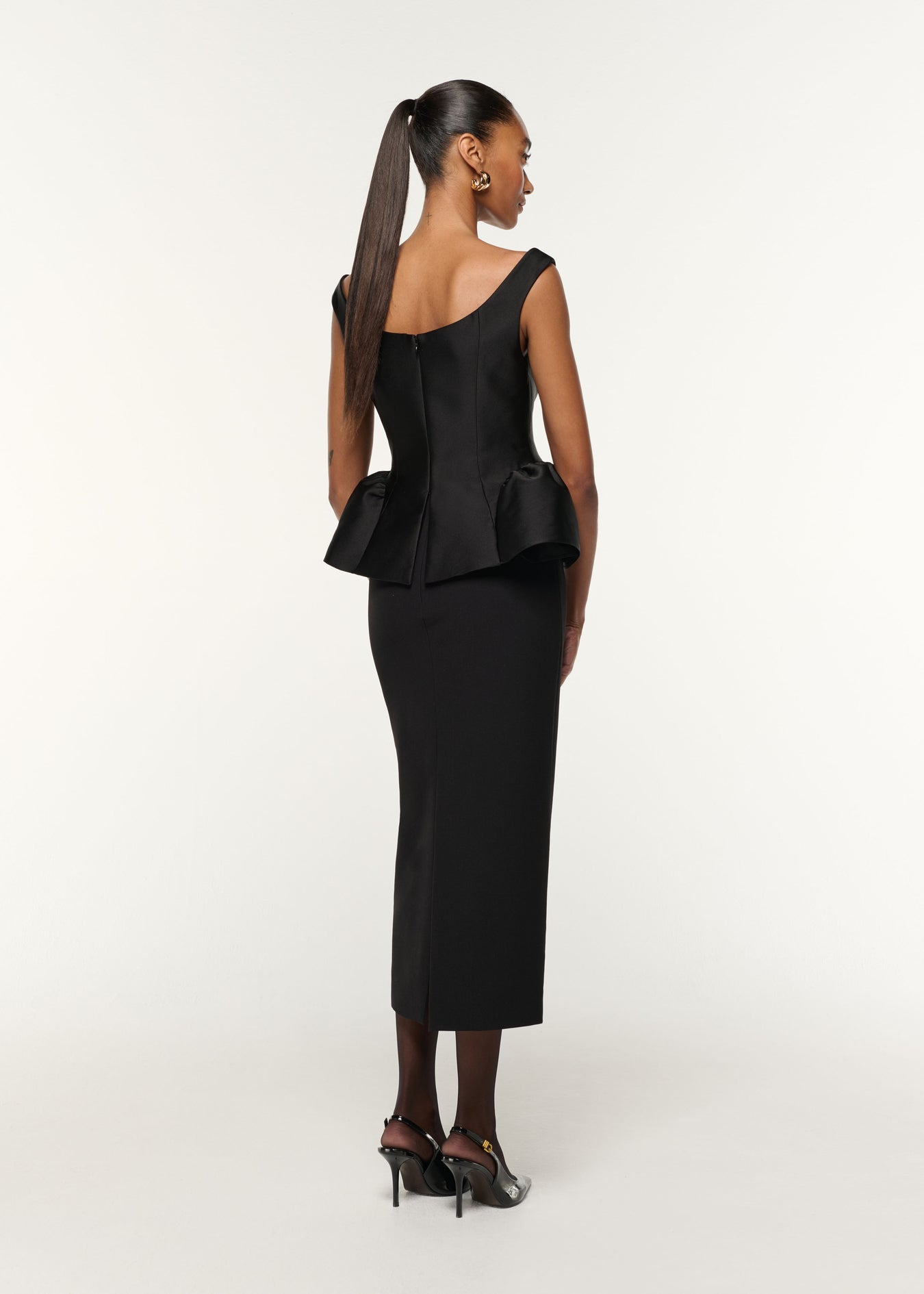 Back view of a model wearing the Crystal Button Peplum Taffeta Crepe Dress in Black