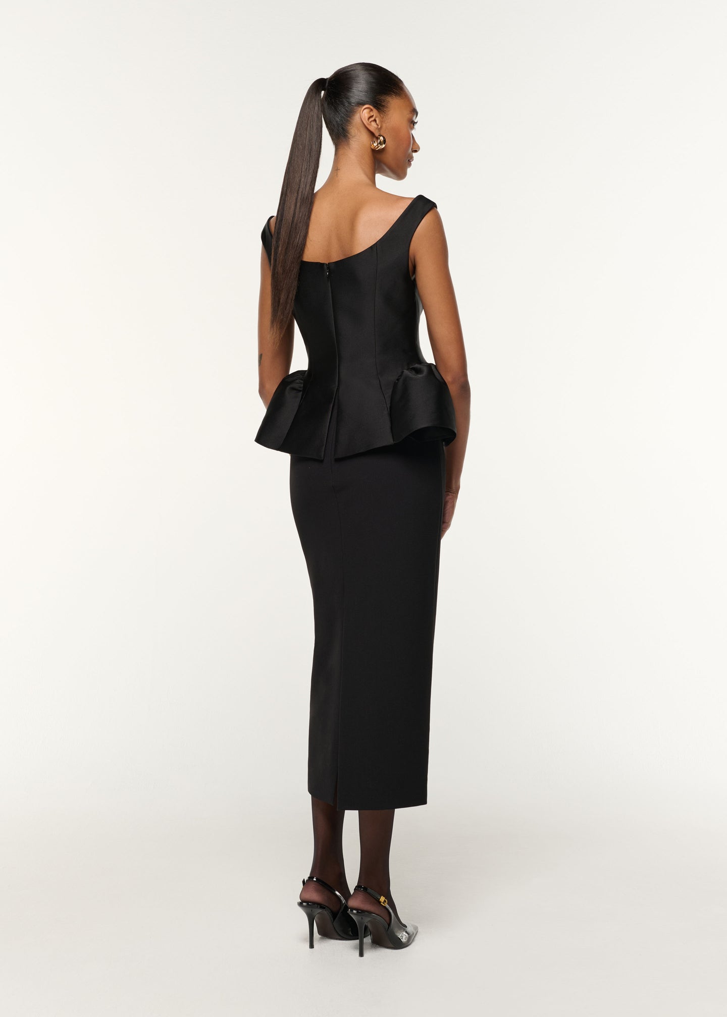 Back view of a model wearing the Crystal Button Peplum Taffeta Crepe Dress in Black