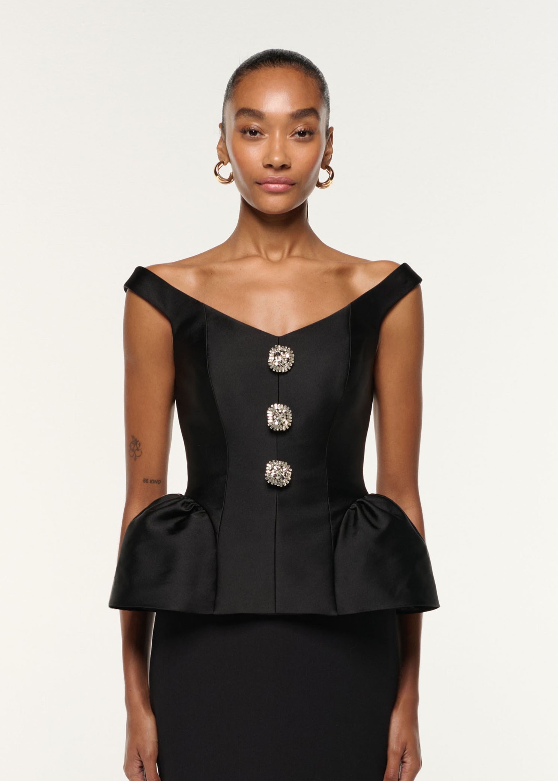 Close up of a model wearing the Crystal Button Peplum Taffeta Crepe Dress in Black