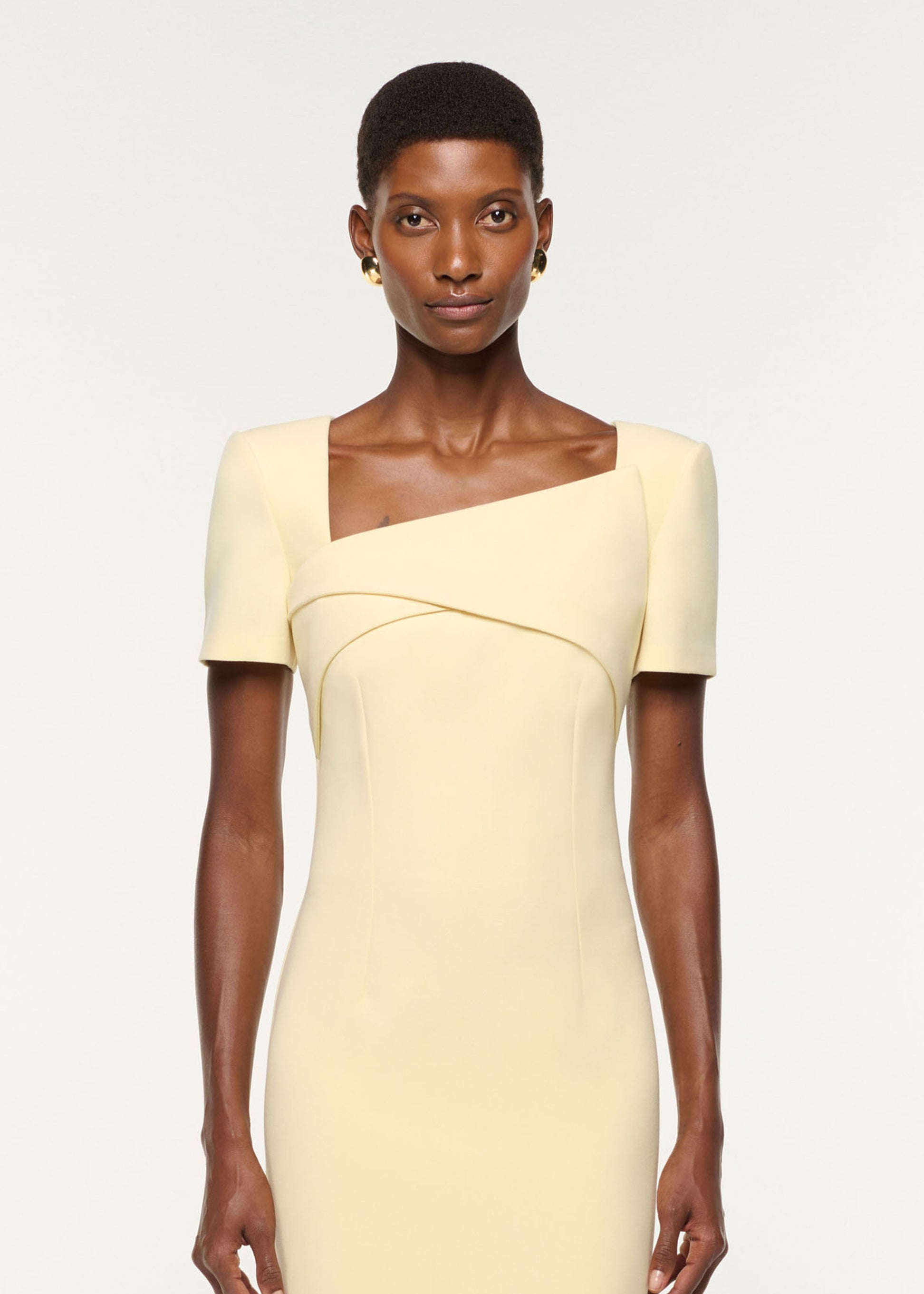 Close up of a model wearing the Asymmetric Drape Crepe Dress in Yellow