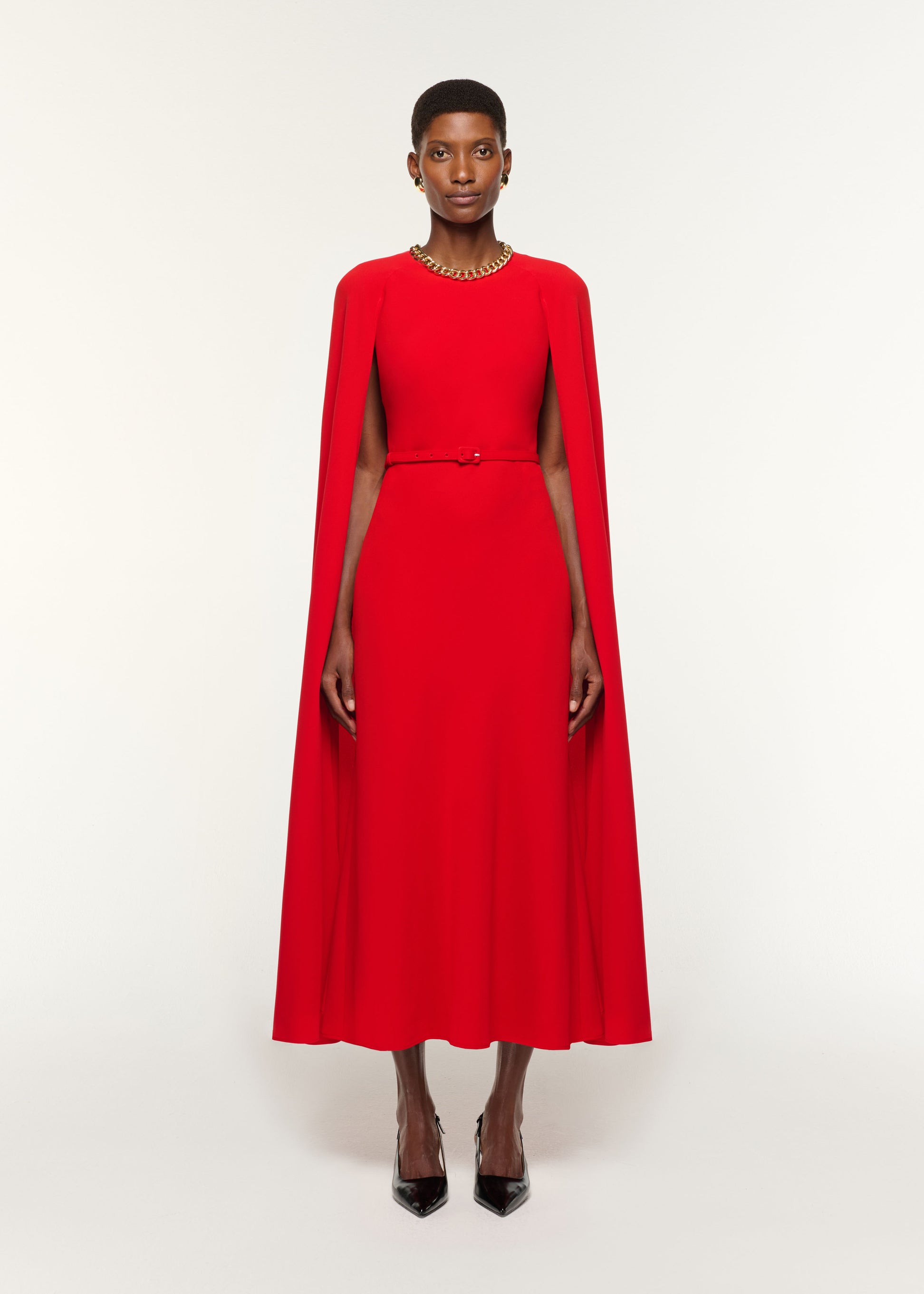 Front view of a model wearing the Light Cady Belted Cape Dress in Red