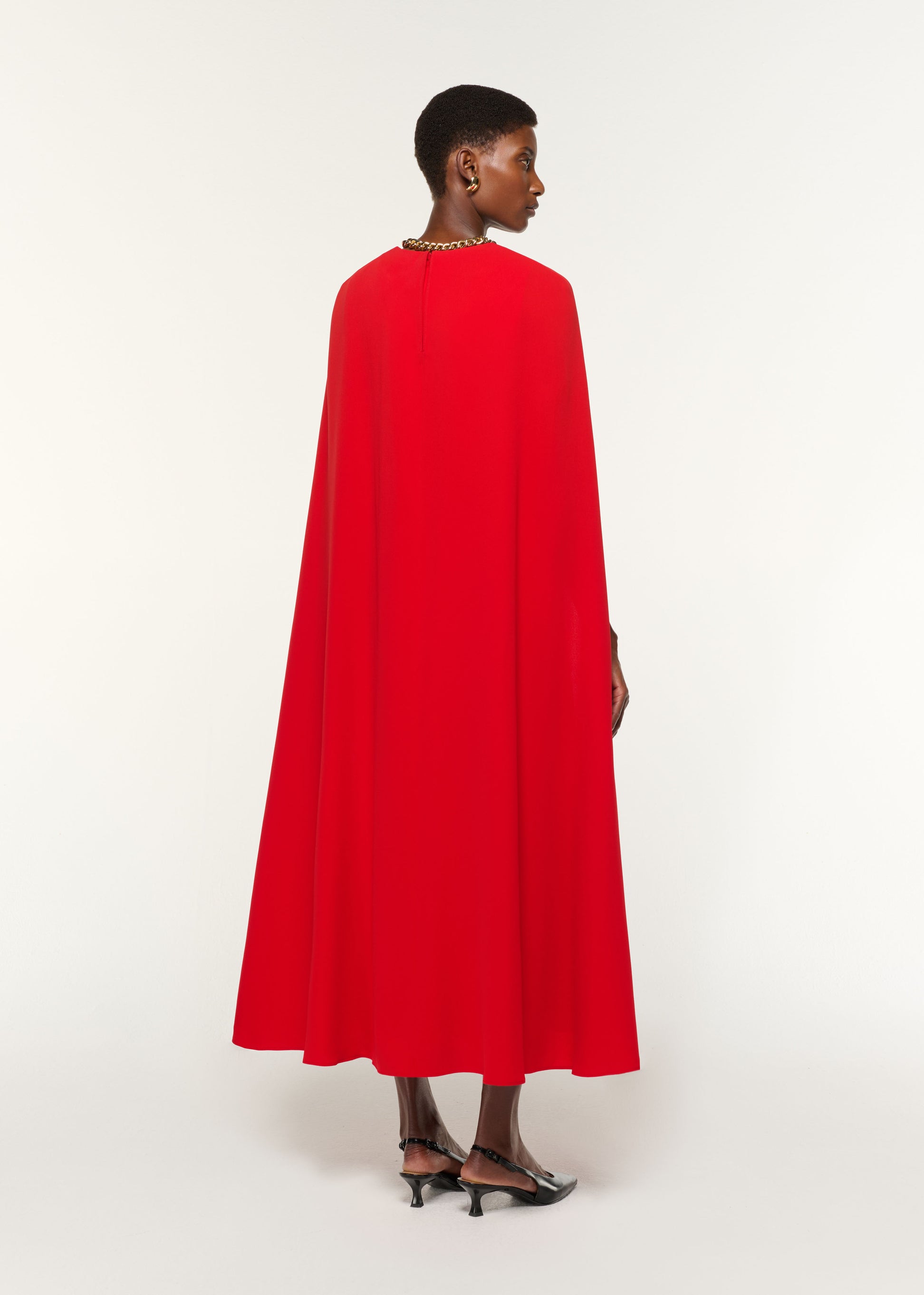 Back view of a model wearing the Light Cady Belted Cape Dress in Red