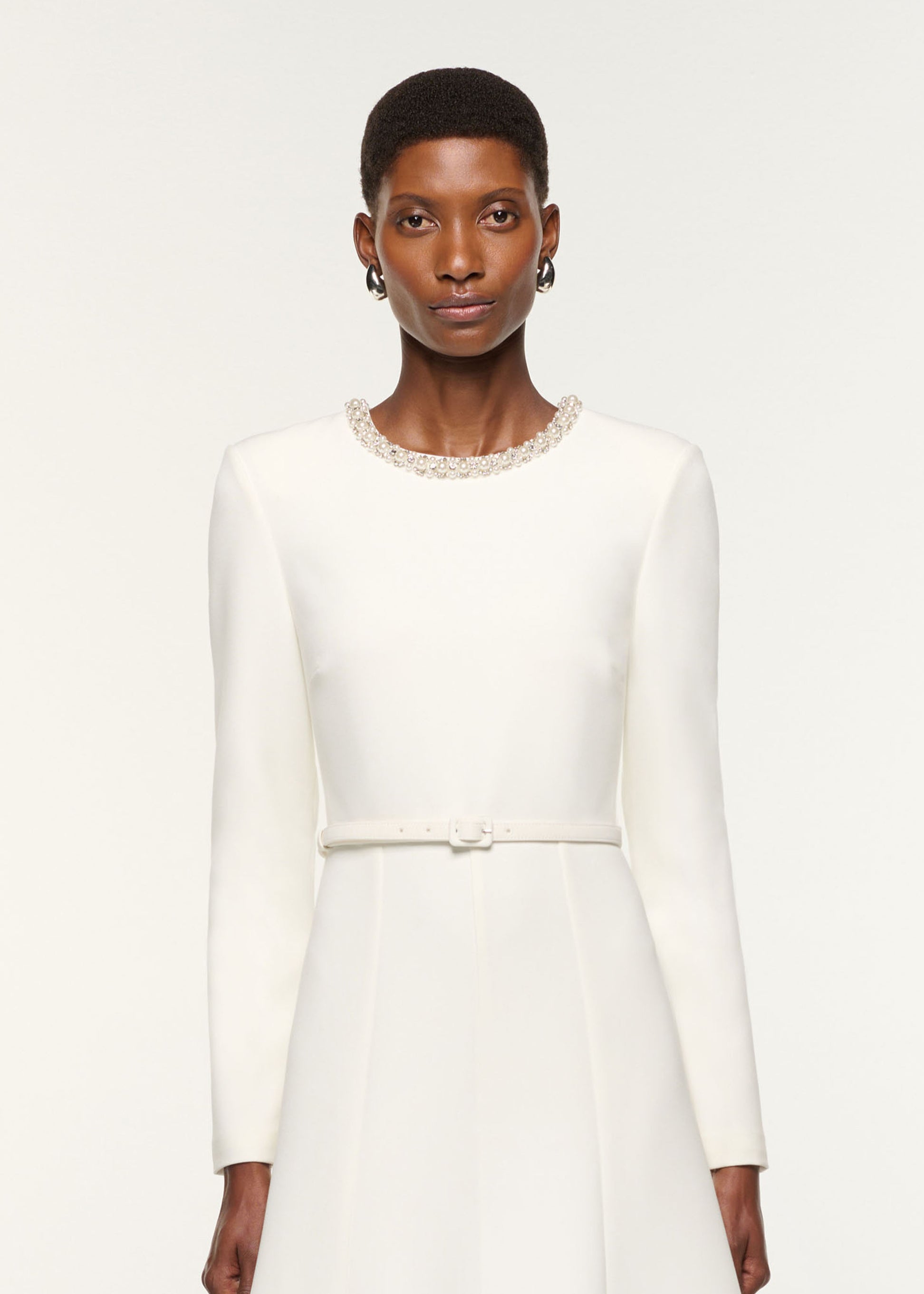 Close up of a model wearing the Crystal Neckline Crepe Dress in White