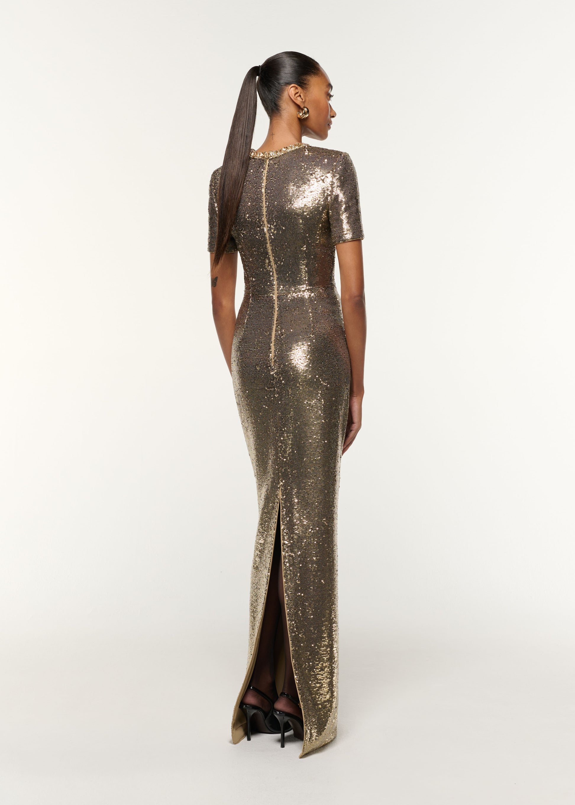 Back view of a model wearing the Crystal Neckline Sequin Column Gown in Gold