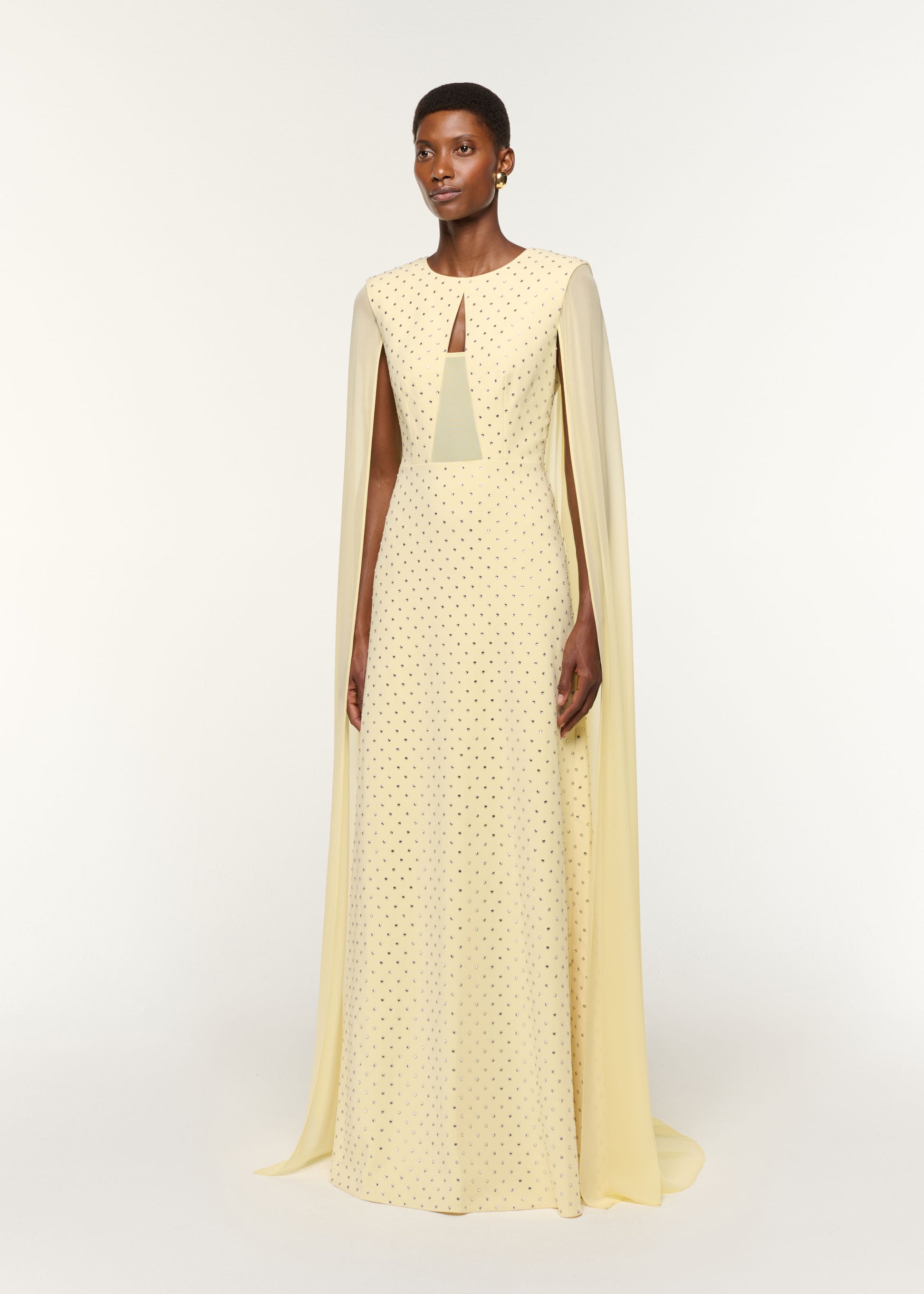 Side view of a model wearing the Chiffon Cape On Diamante Crepe Gown in Yellow
