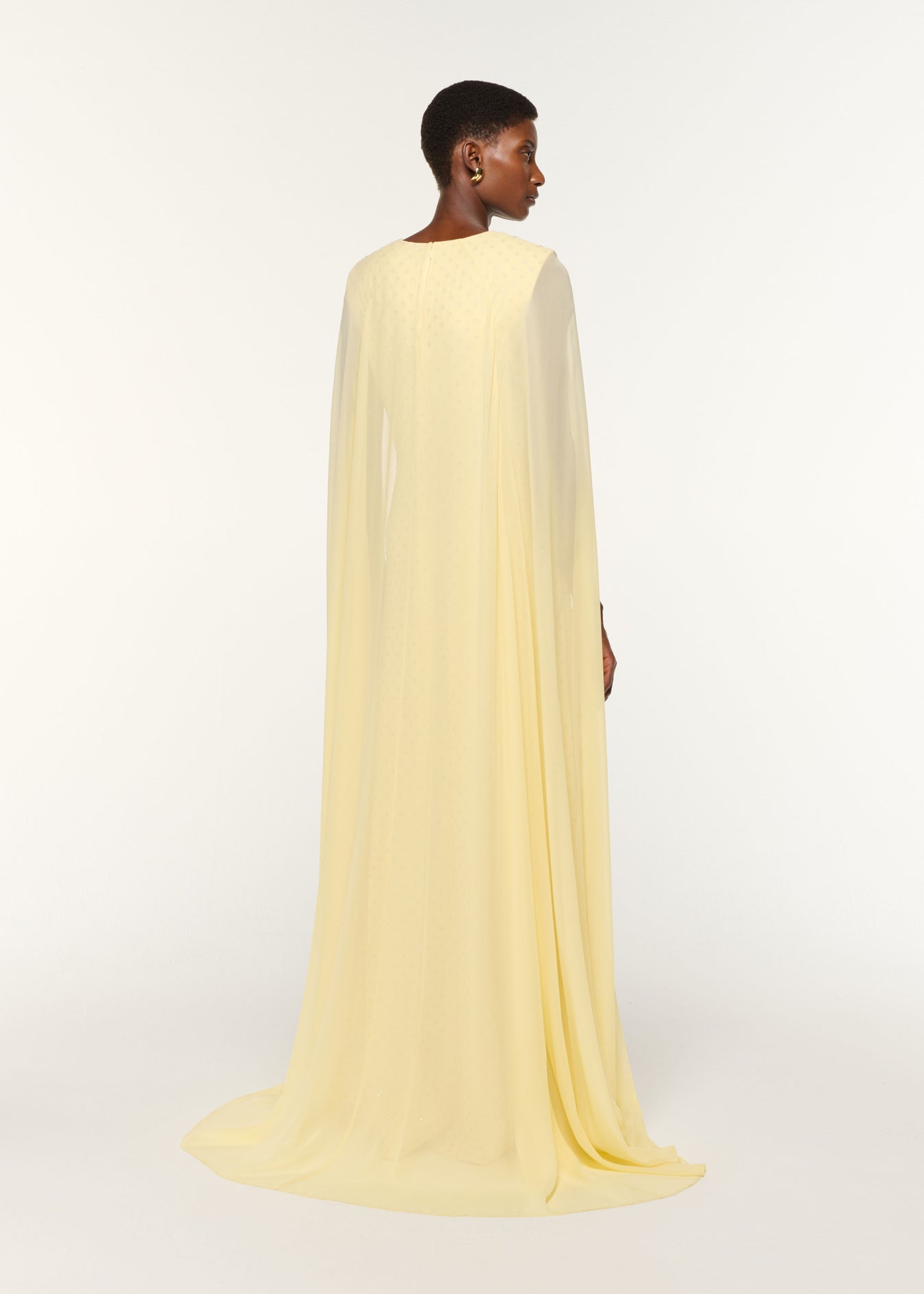 Back view of a model wearing the Chiffon Cape On Diamante Crepe Gown in Yellow