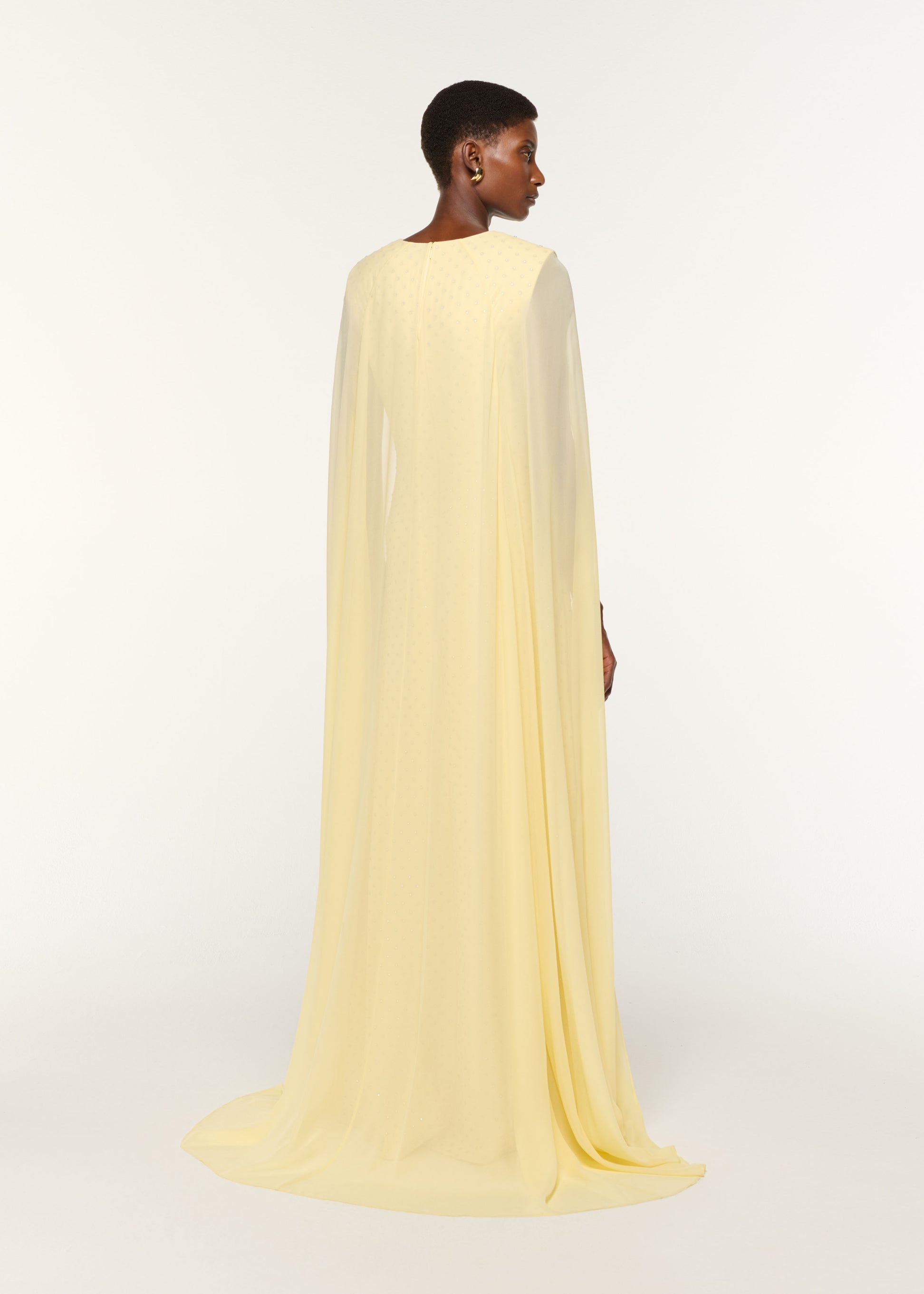 Back view of a model wearing the Chiffon Cape On Diamante Crepe Gown in Yellow