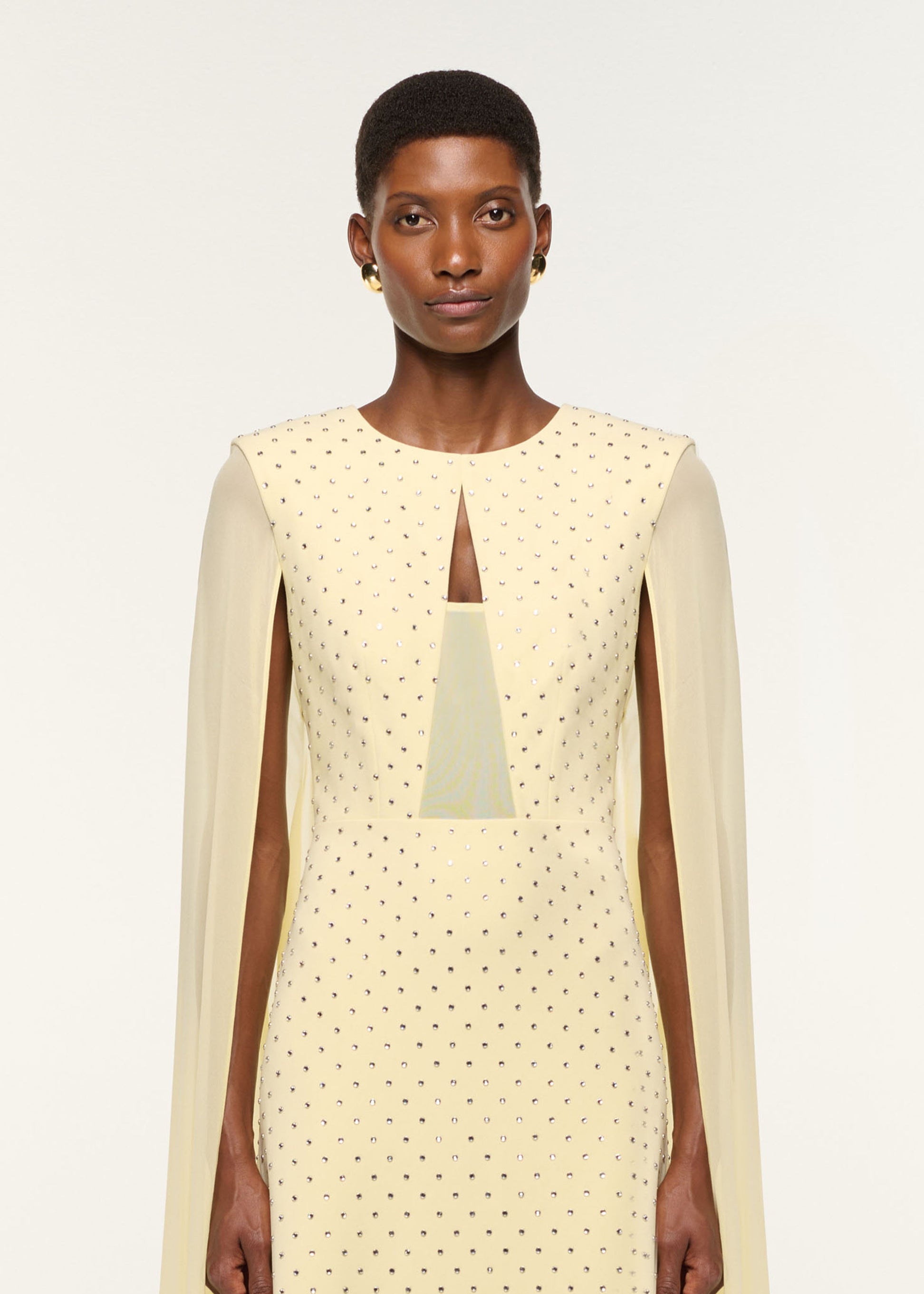 Close up of a model wearing the Chiffon Cape On Diamante Crepe Gown in Yellow