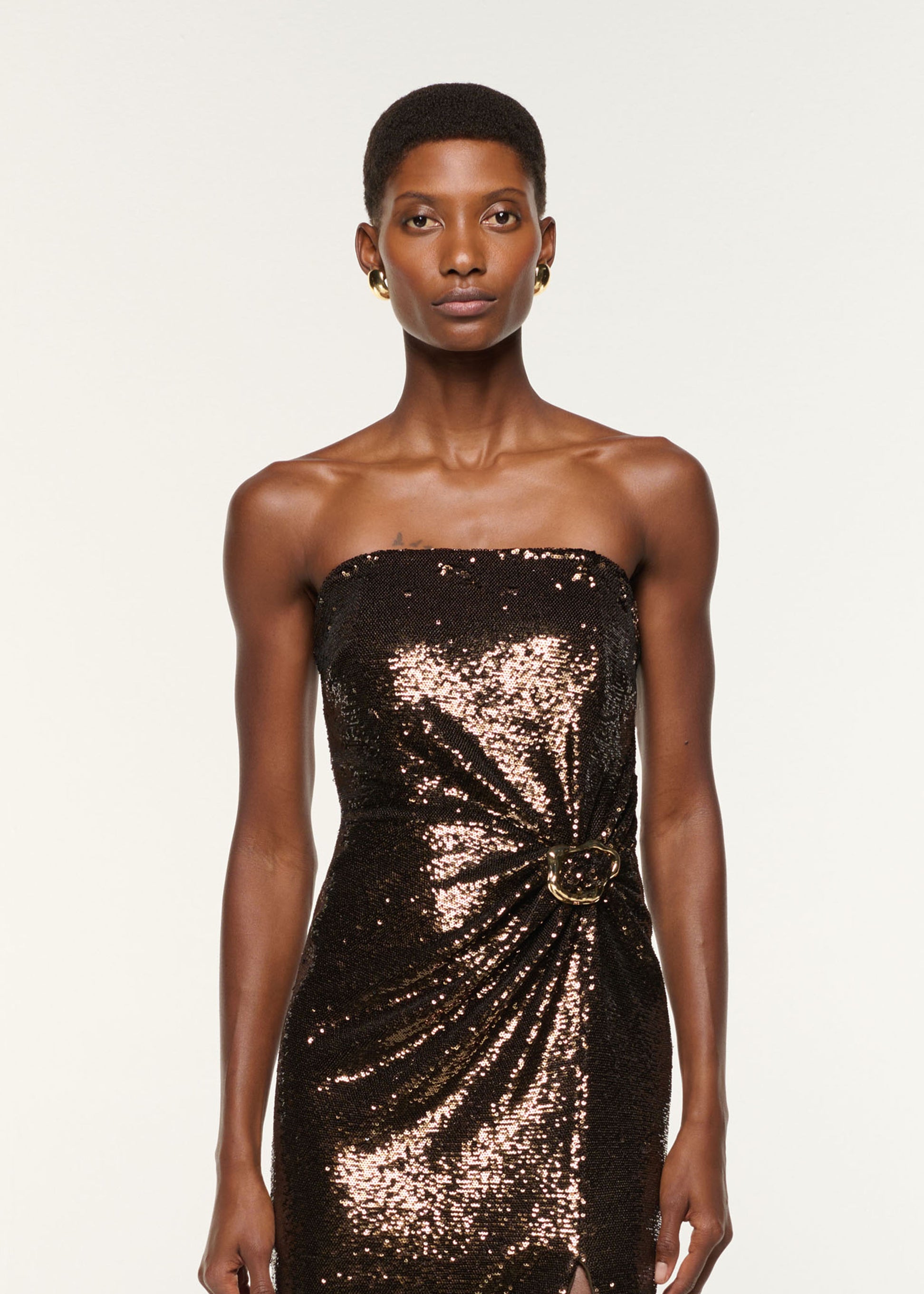 Close up of a model wearing the Strapless Sequin Buckle Gown in Bronze