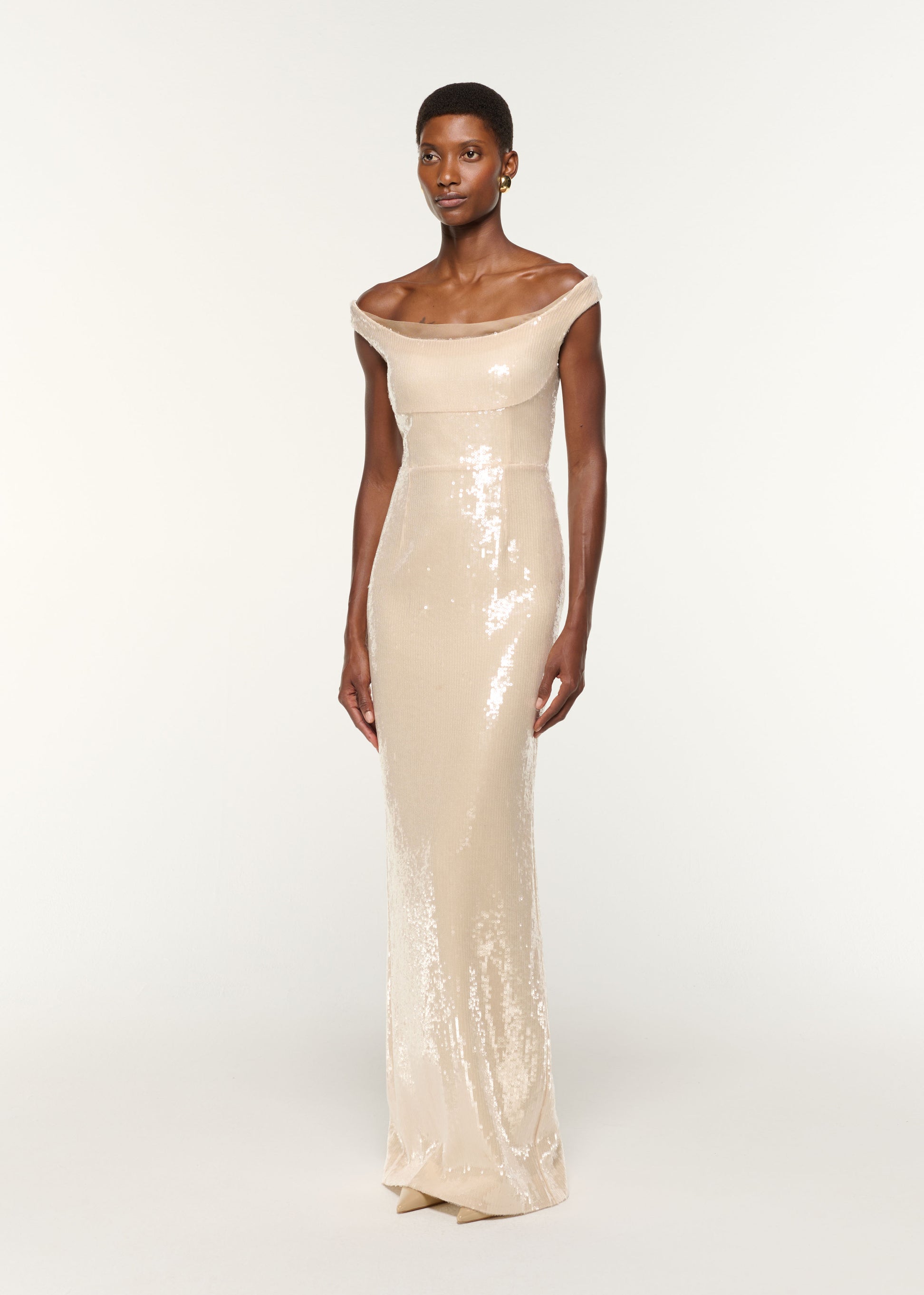 Side view of a model wearing the Off The Shoulder Sequin Gown in Cream
