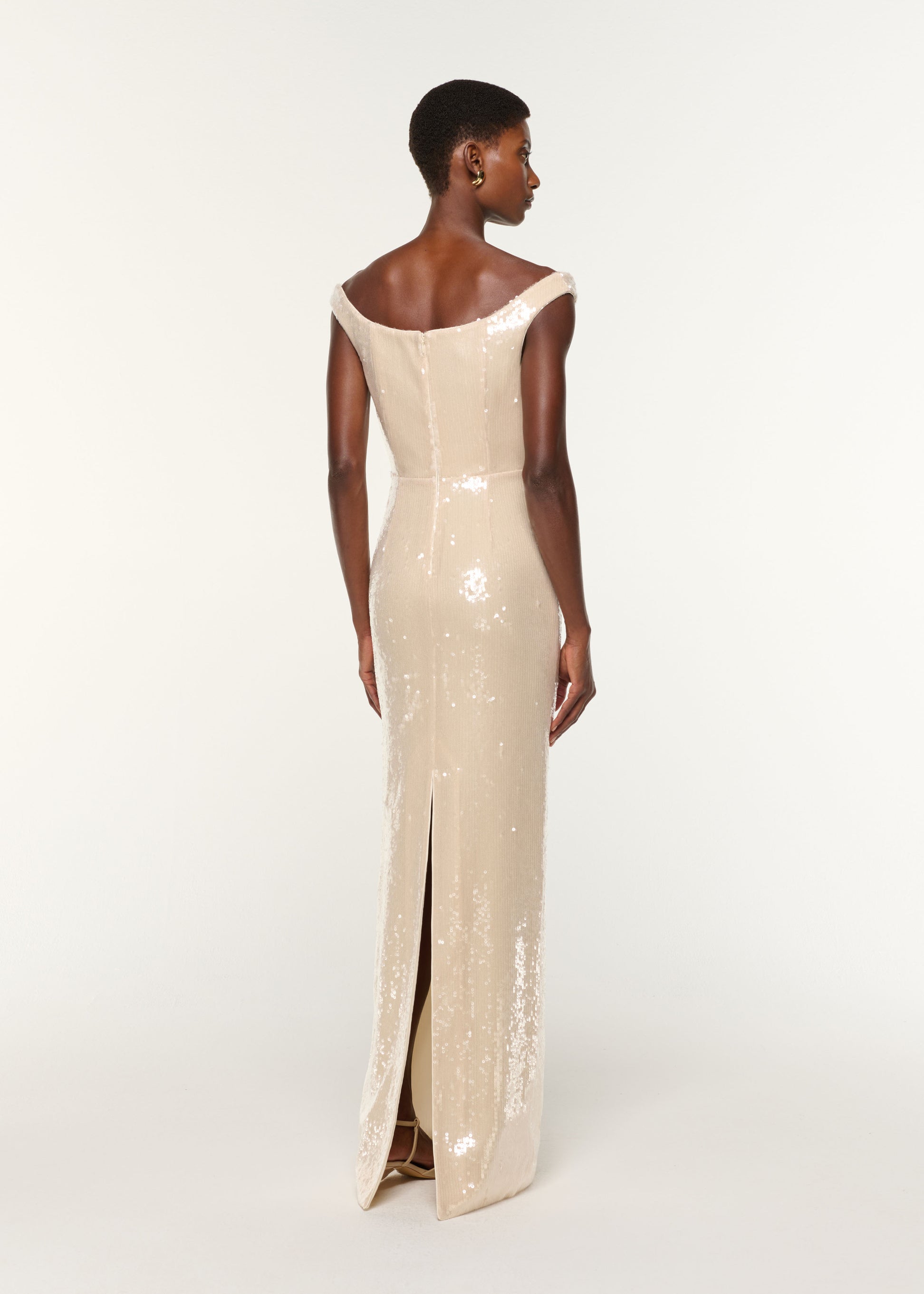 Back view of a model wearing the Off The Shoulder Sequin Gown in Cream