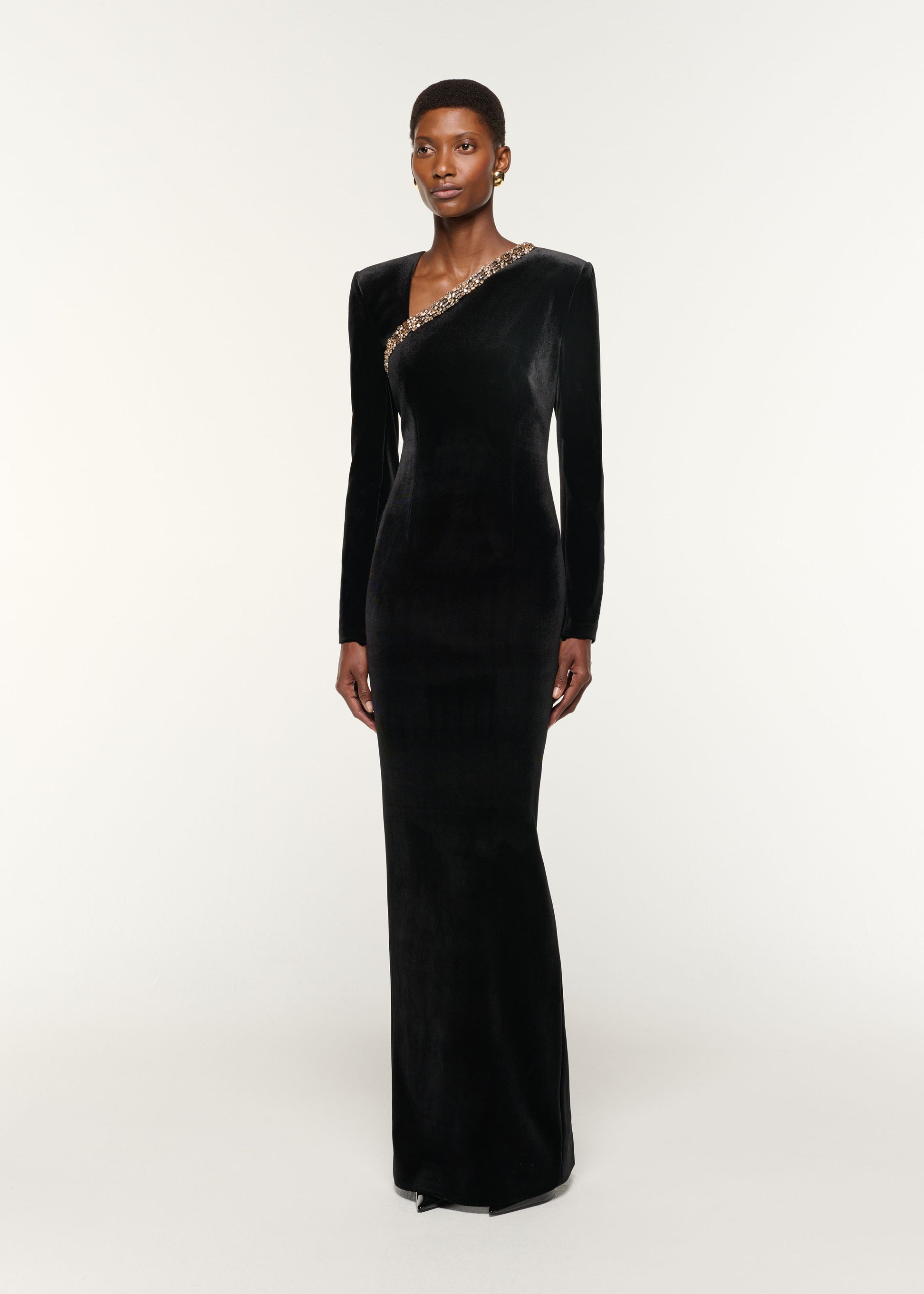 Side view of a model wearing the Long Sleeve Embellished Velvet Gown in Black