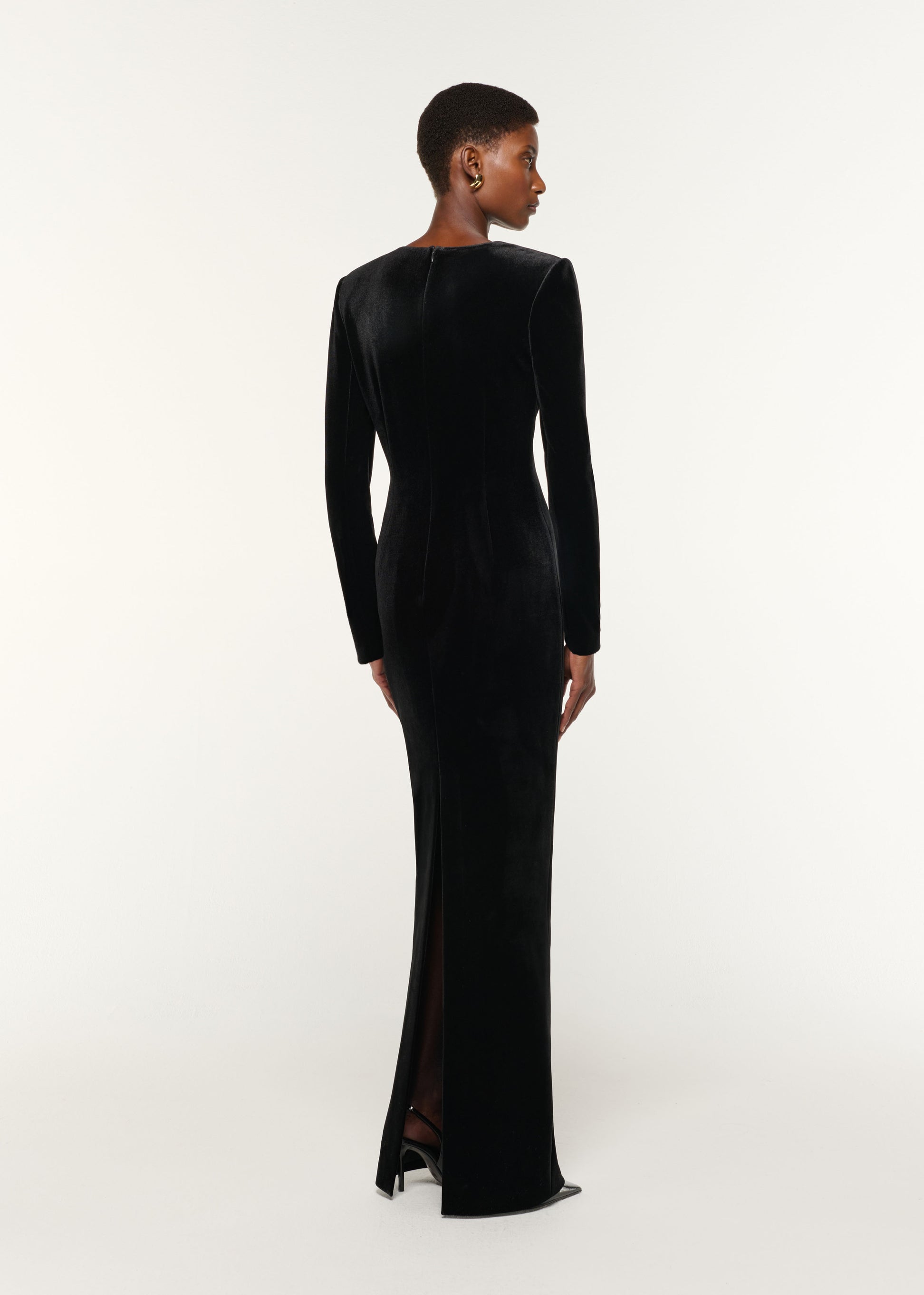 Back view of a model wearing the Long Sleeve Embellished Velvet Gown in Black