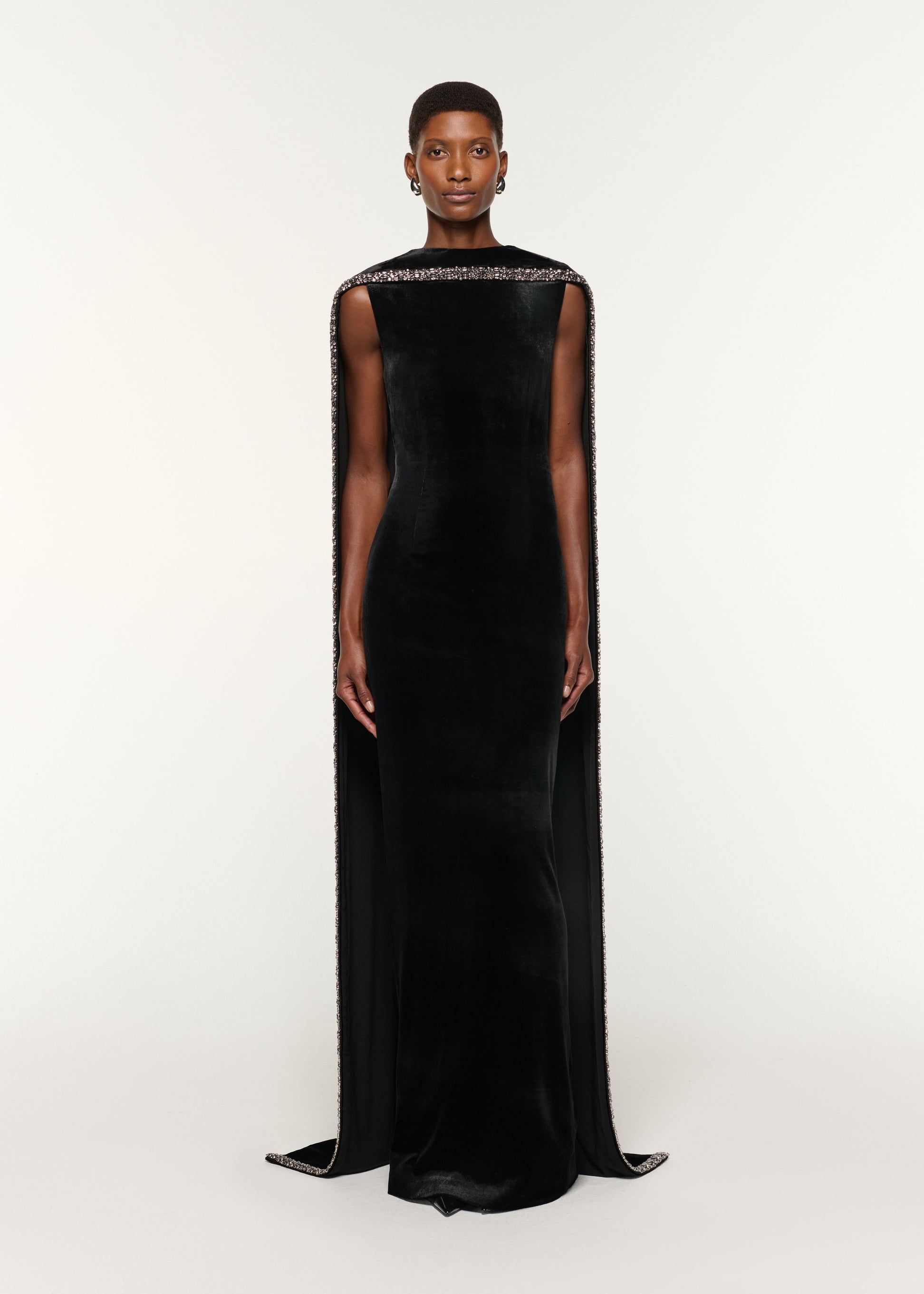 Front view of a model wearing the Embellished Cape Velvet Gown in Black