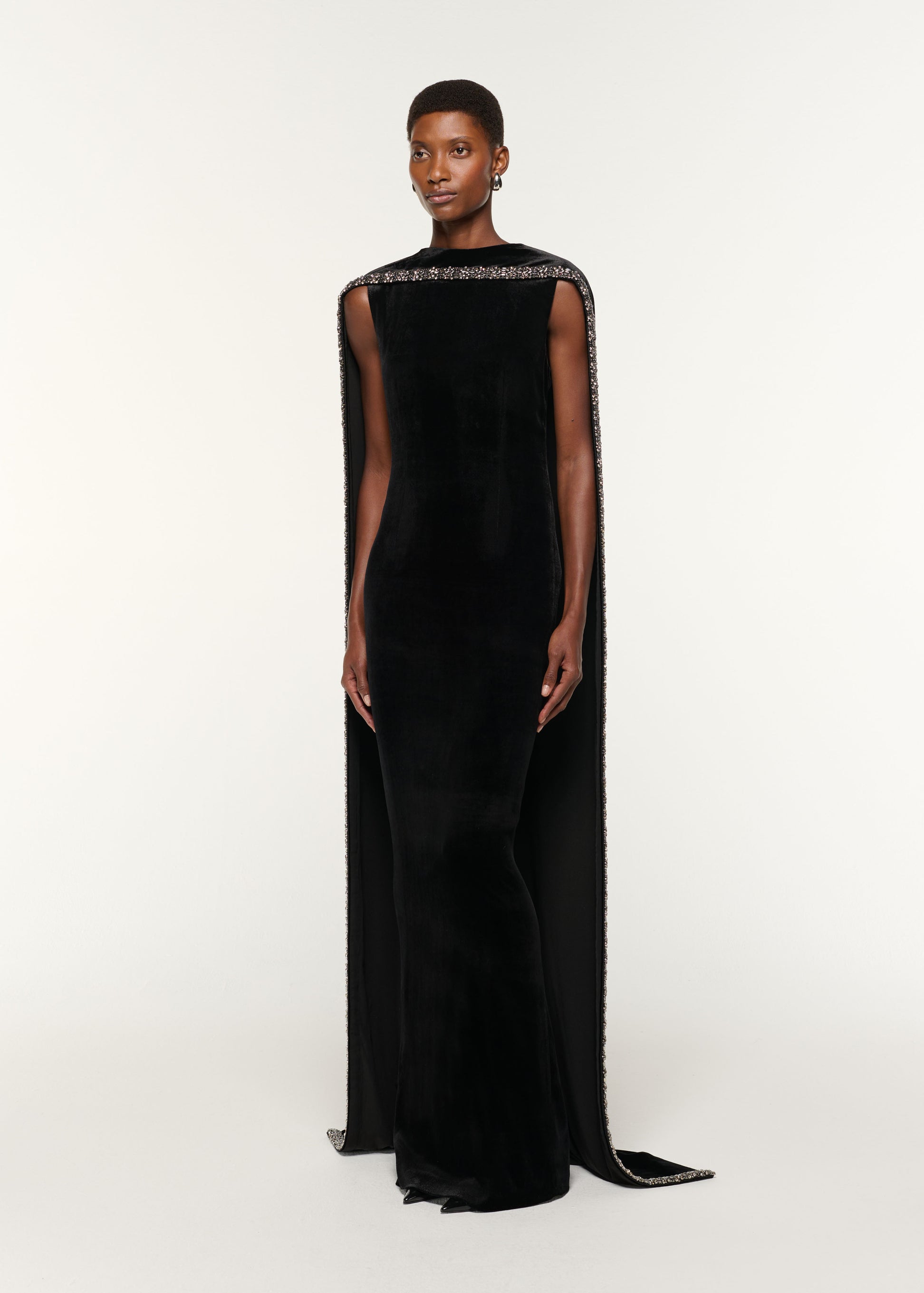 Side view of a model wearing the Embellished Cape Velvet Gown in Black