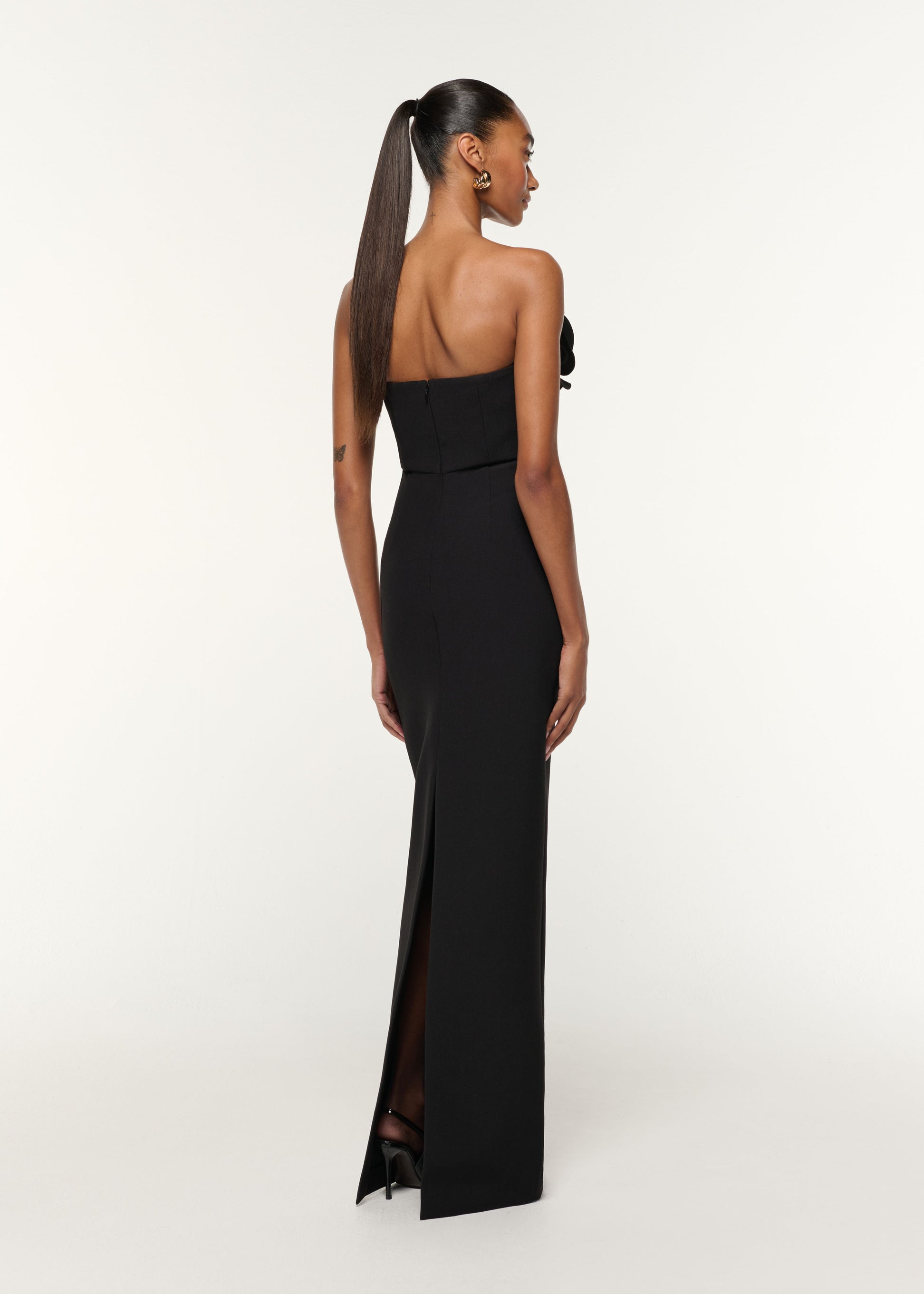 Back view of a model wearing the Flower Detail Strapless Gown in Black