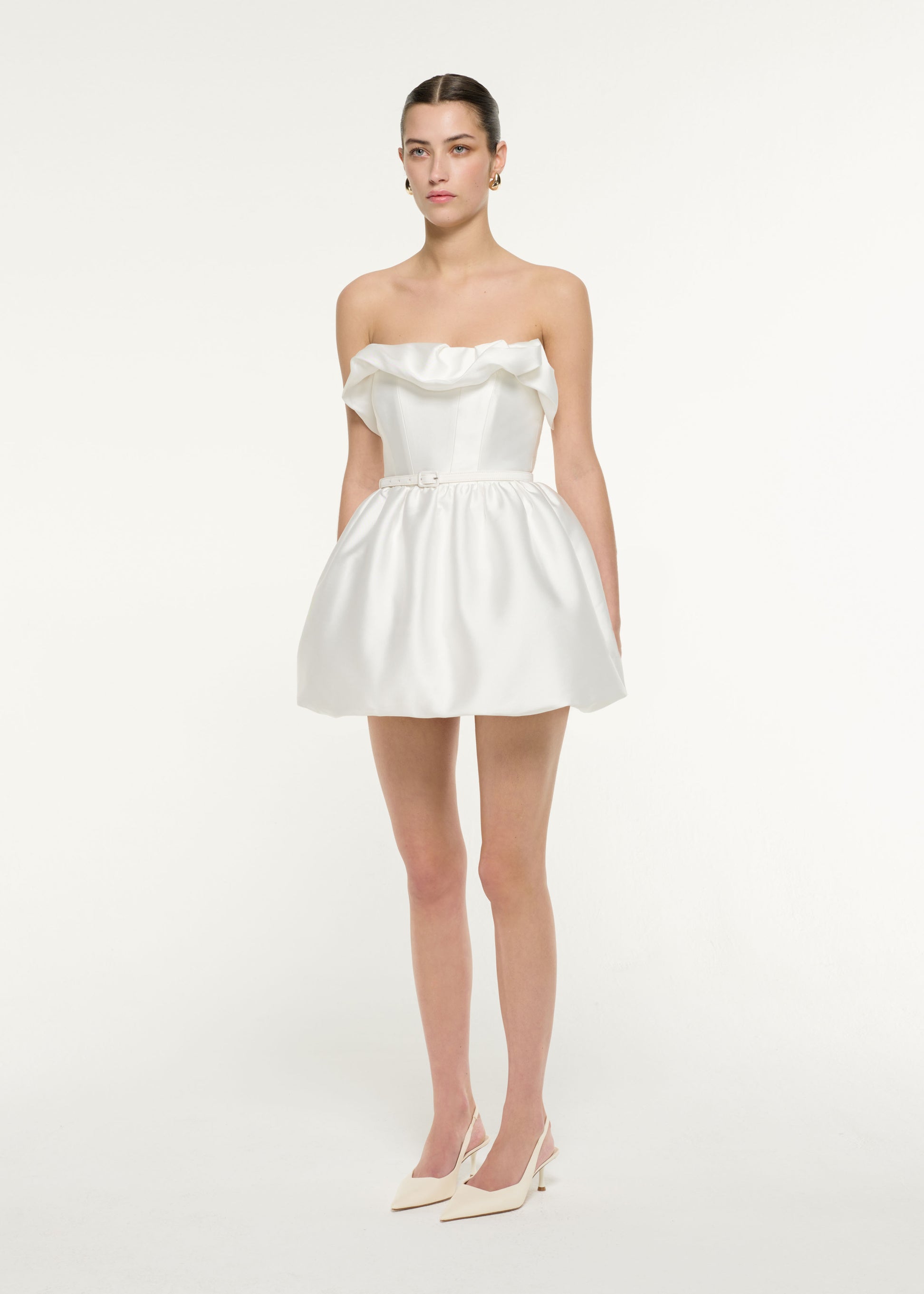 Side view of a model wearing the Ruffle Mini Dress in White