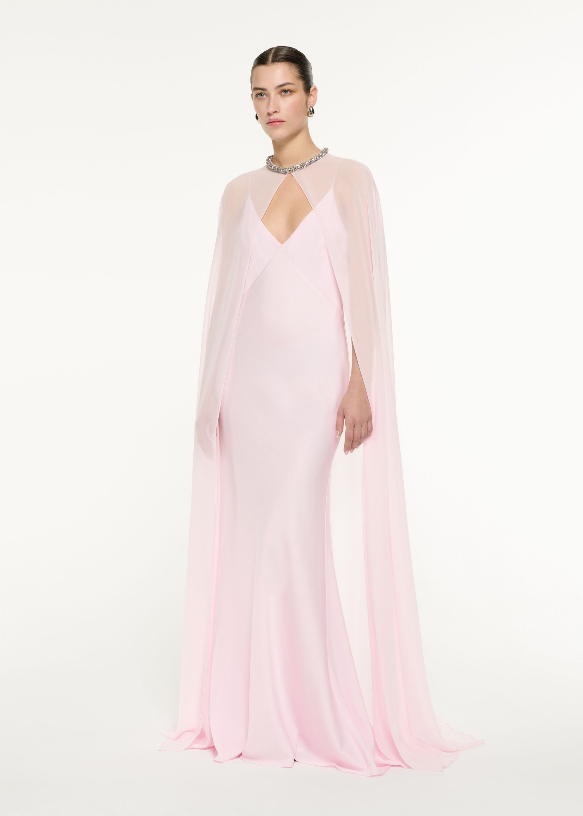 Side view of a model wearing the Satin Crepe Cape Gown in Light Pink