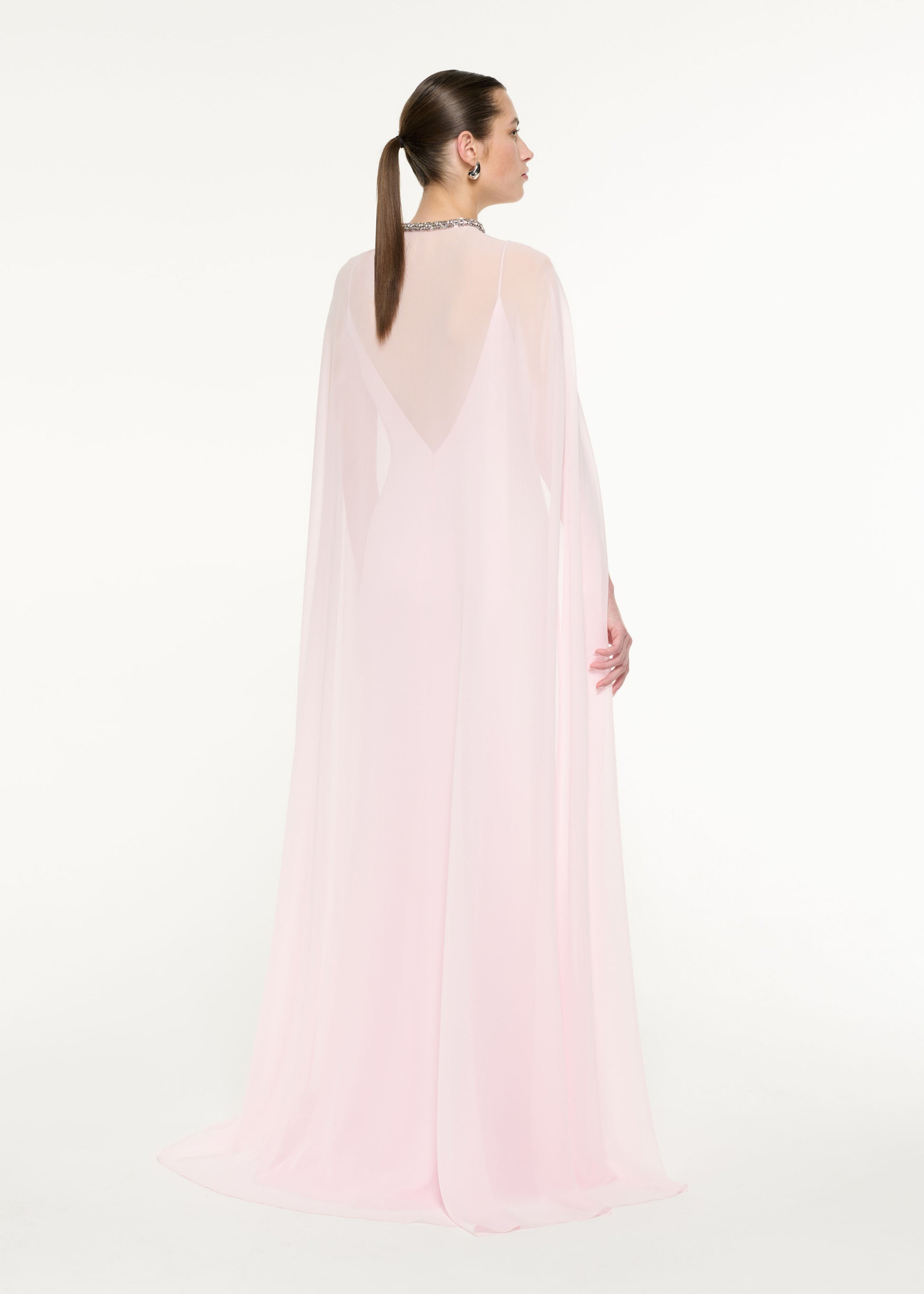 Back view of a model wearing the Satin Crepe Cape Gown in Light Pink