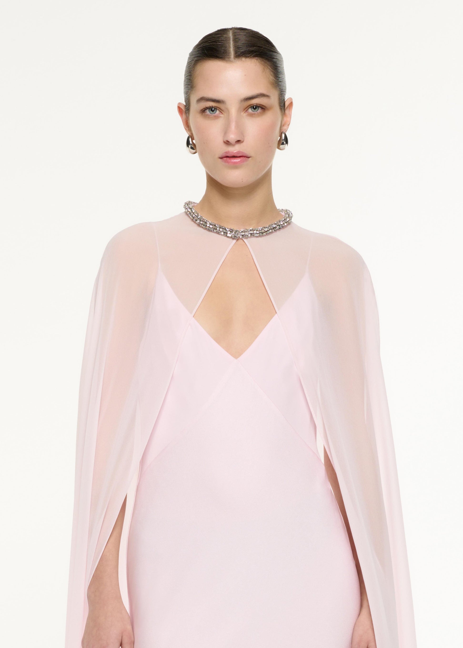 Close up of a model wearing the Satin Crepe Cape Gown in Light Pink