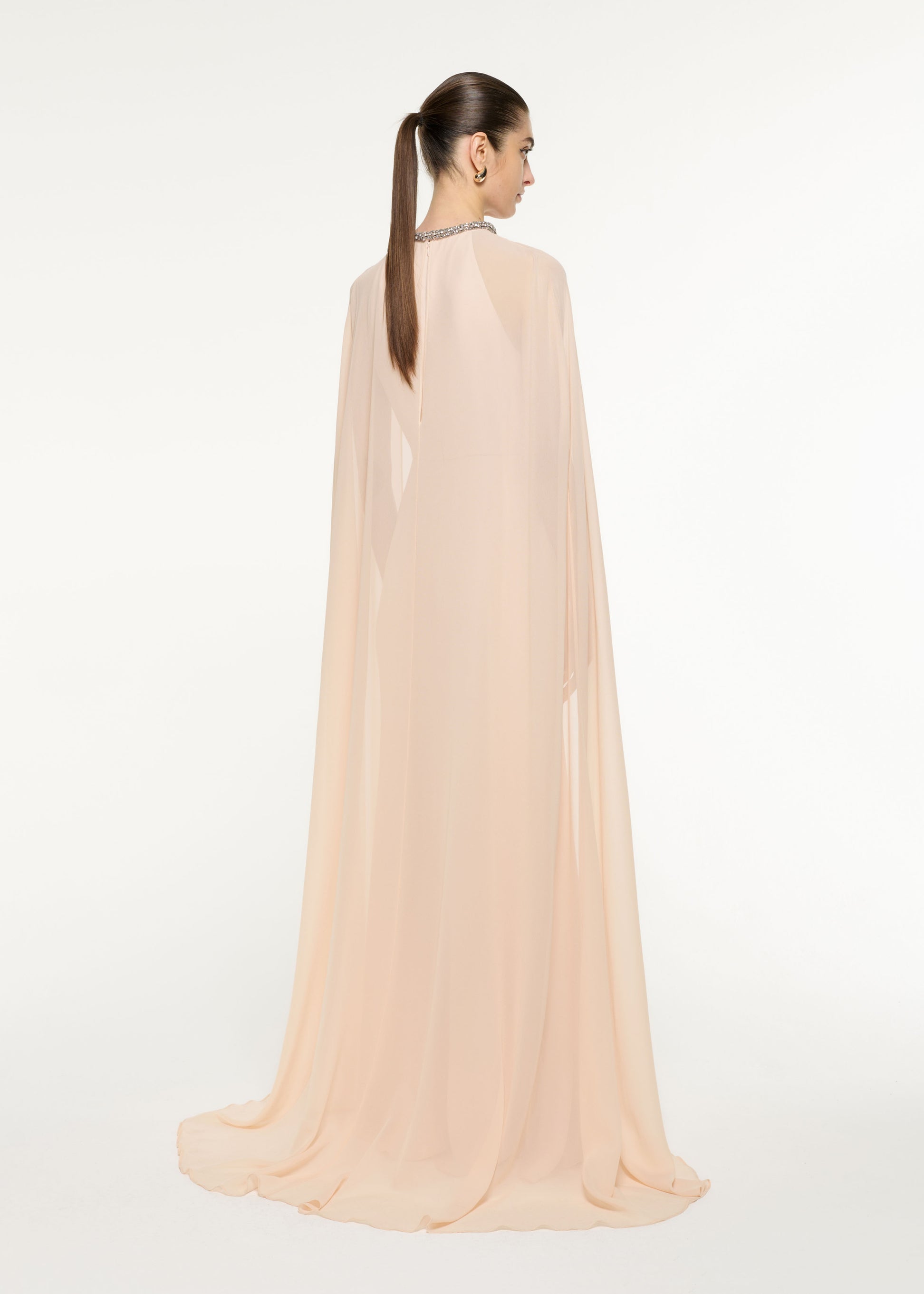 Back view of a model wearing the Silk Chiffon Cape Dress in Nude