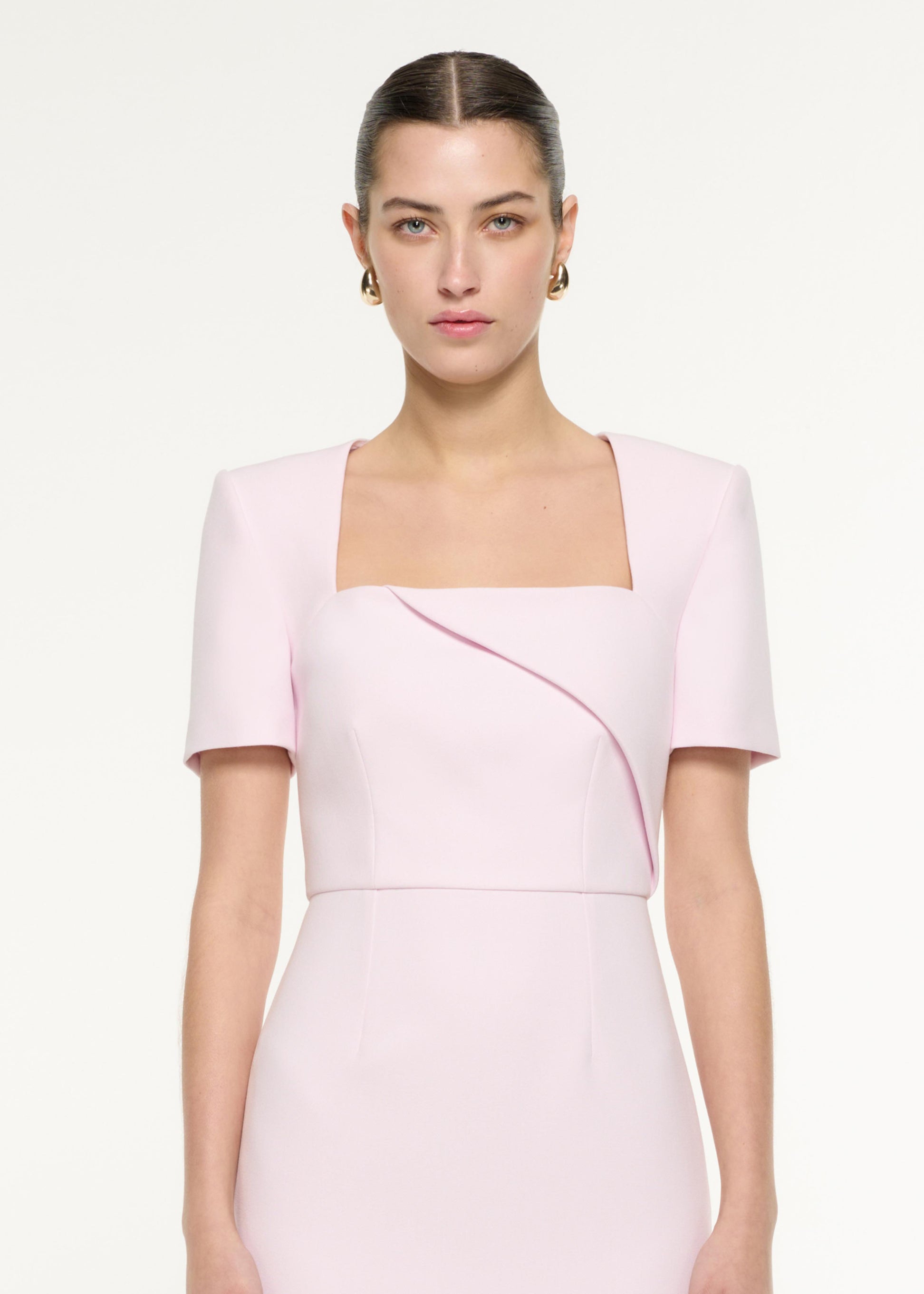 Close up of a model wearing the Diagonal Fold Midi Dress in Light Pink