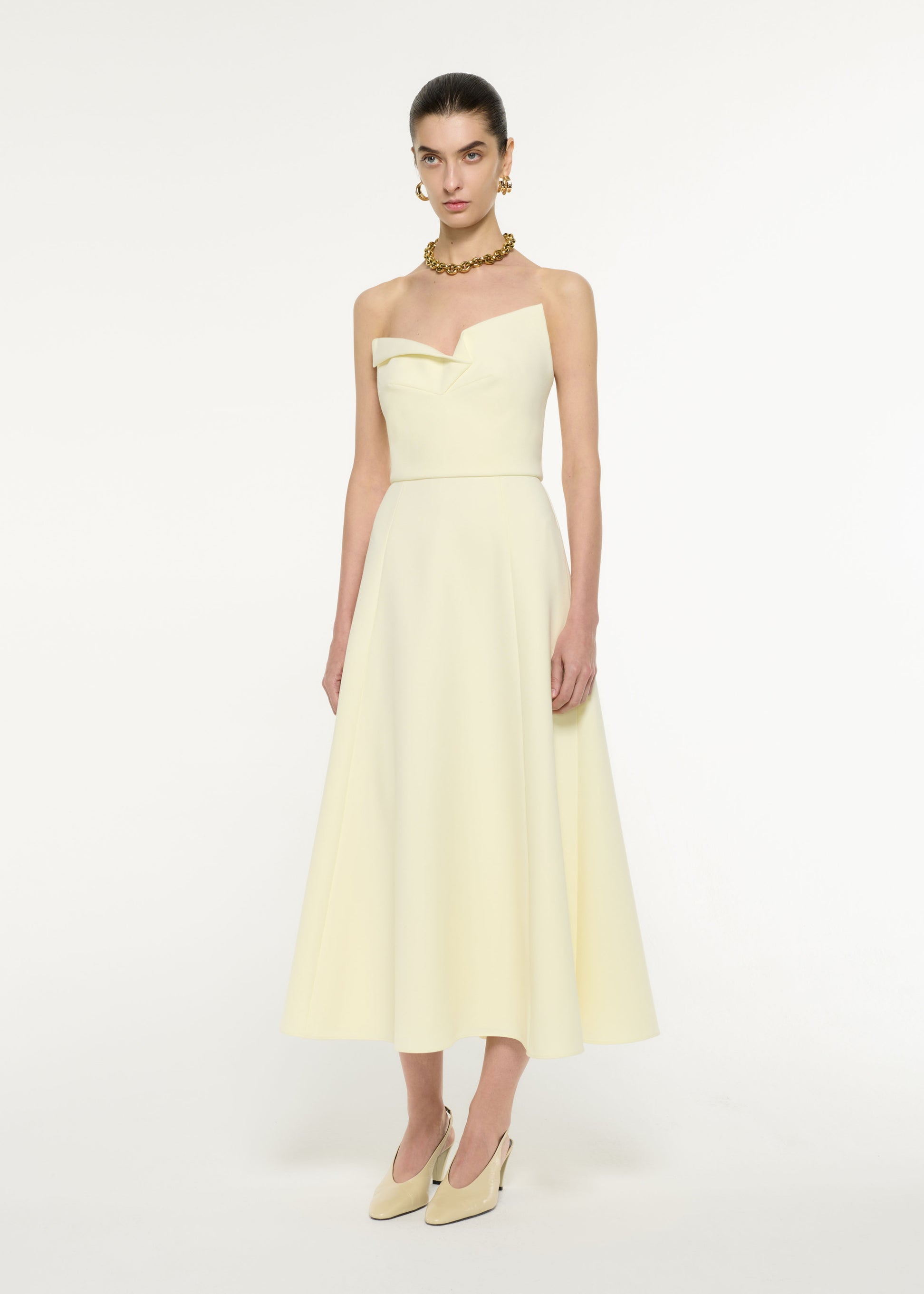Side view of a model wearing the Strapless Drape Crepe Midi Dress in Light Yellow