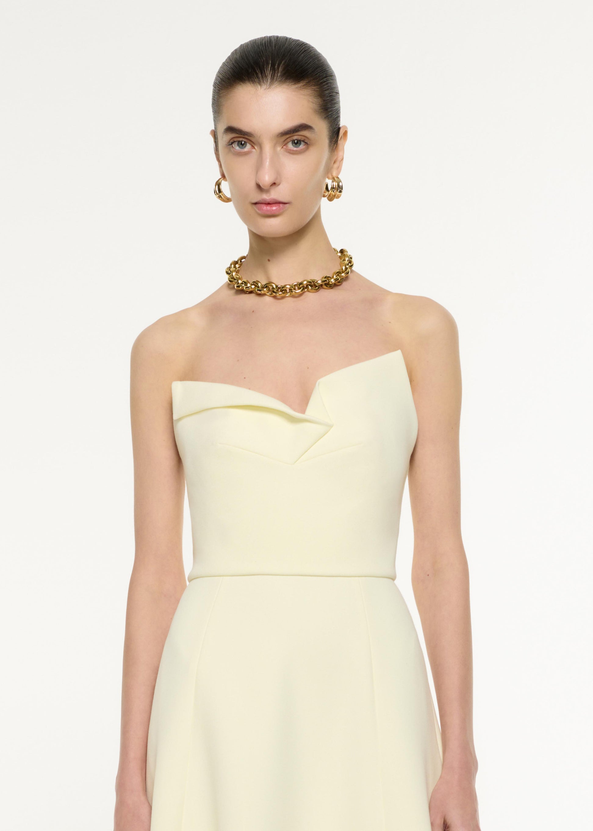 Close up of a model wearing the Strapless Drape Crepe Midi Dress in Light Yellow