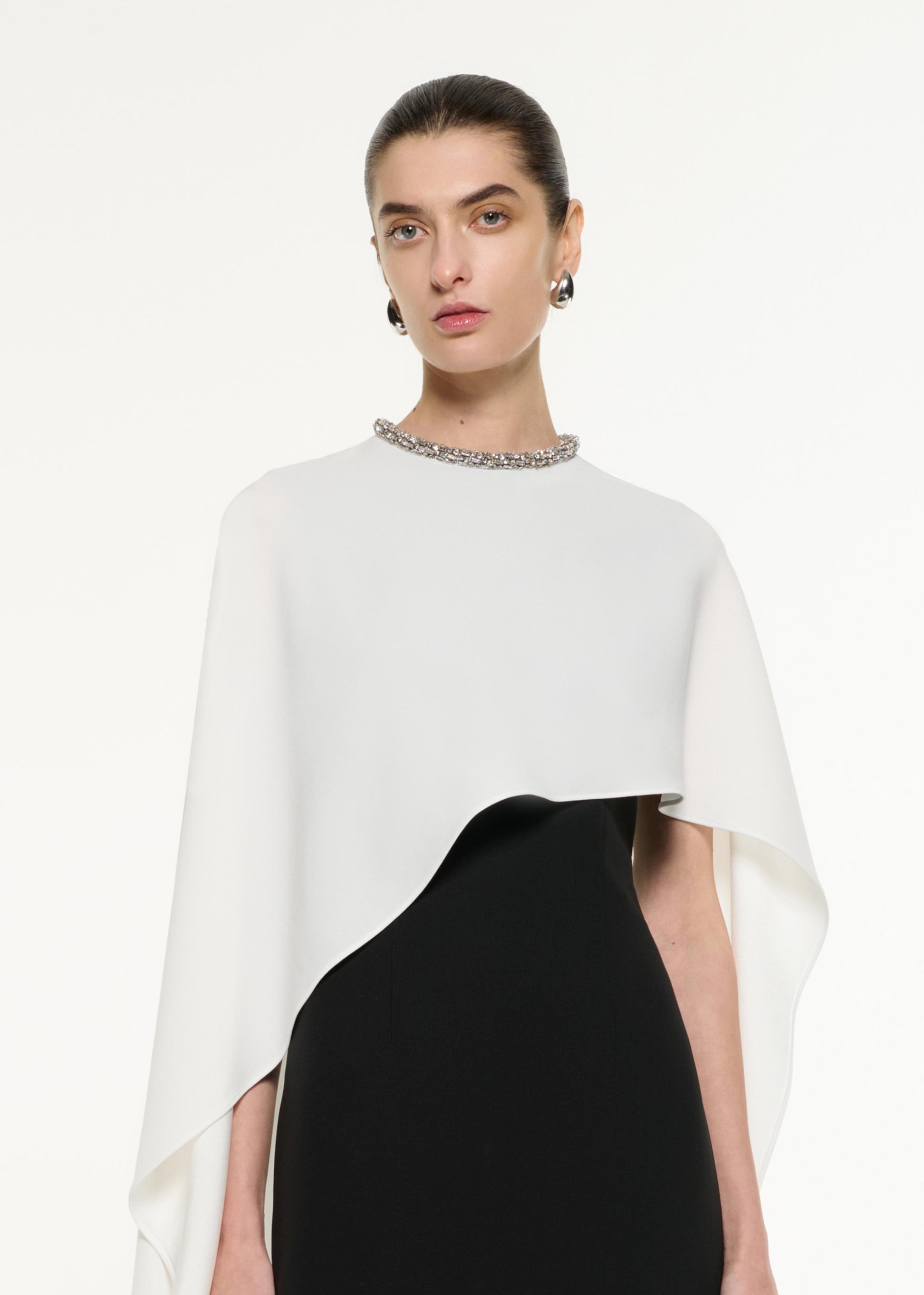 Close up of a model wearing the Satin Crepe Cape Gown in Monocrhome