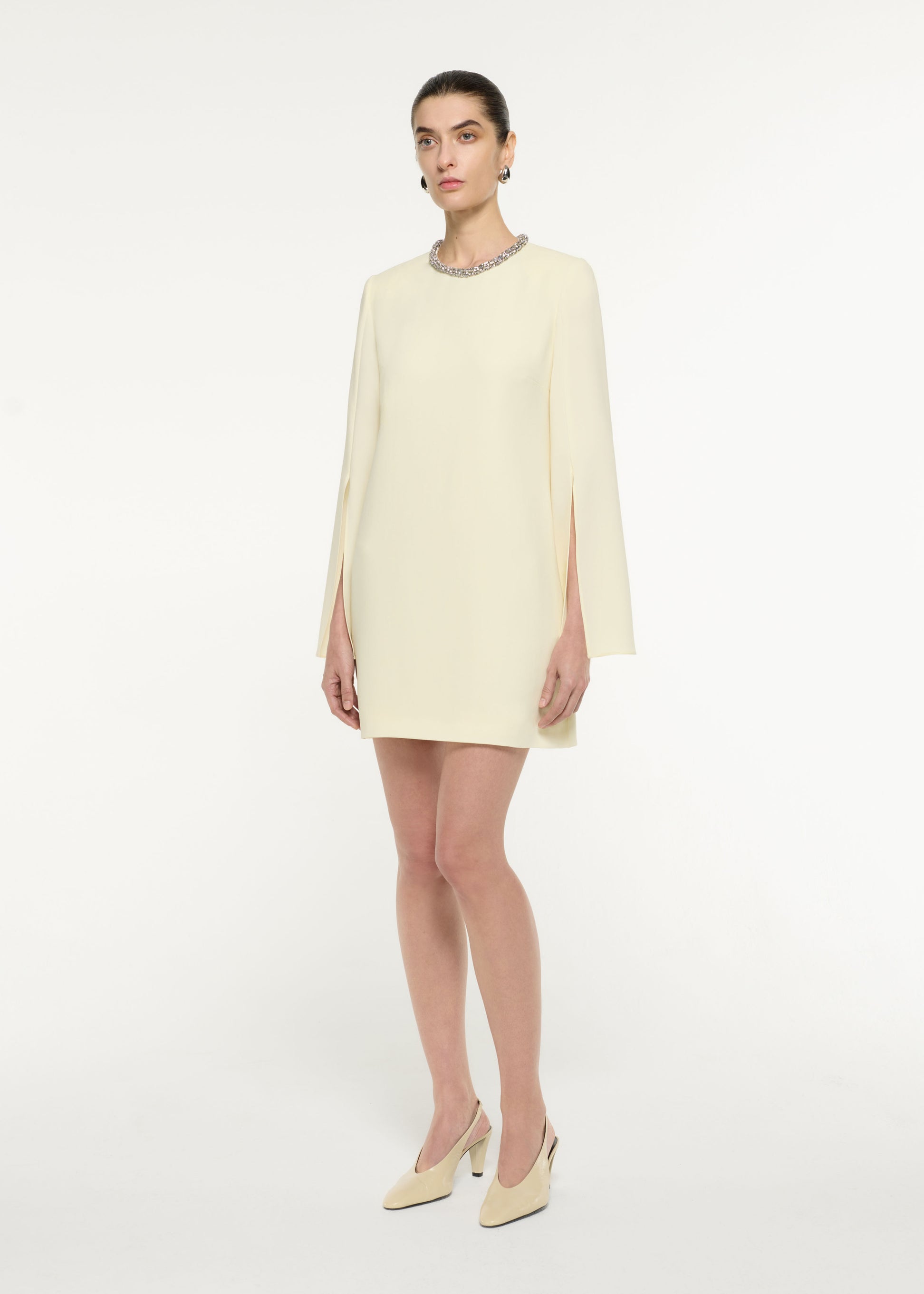 Side view of a model wearing the Cape Sleeve Embellished Mini Dress in Light Yellow
