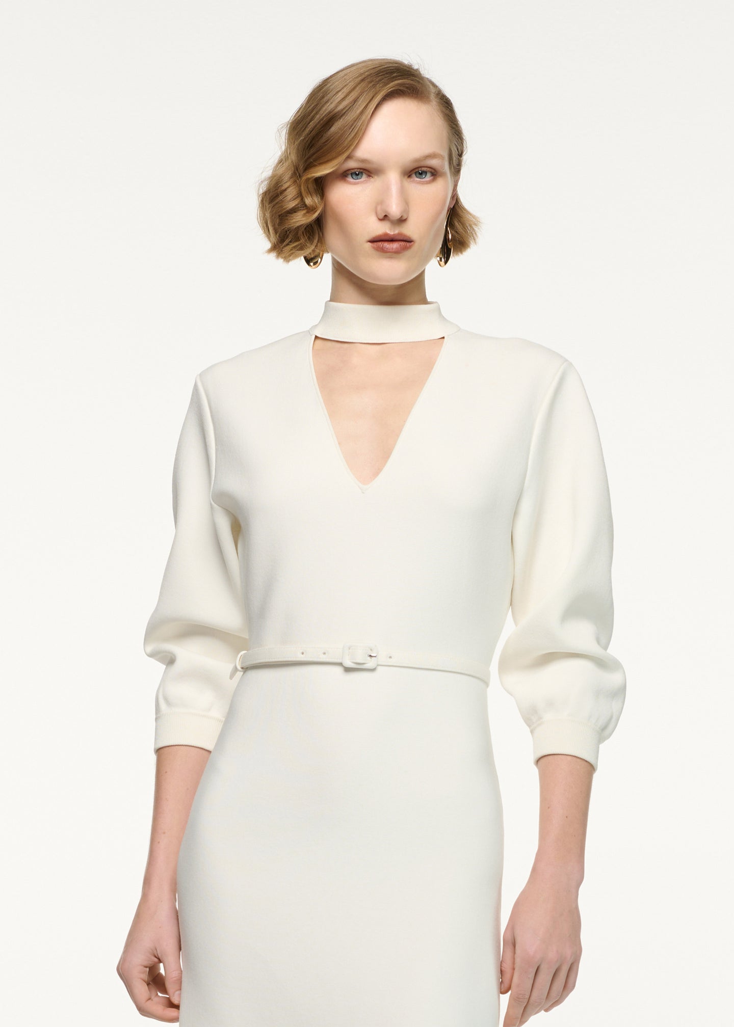 Close up of a model wearing the Belted Blouson Knit Midi Dress in Cream